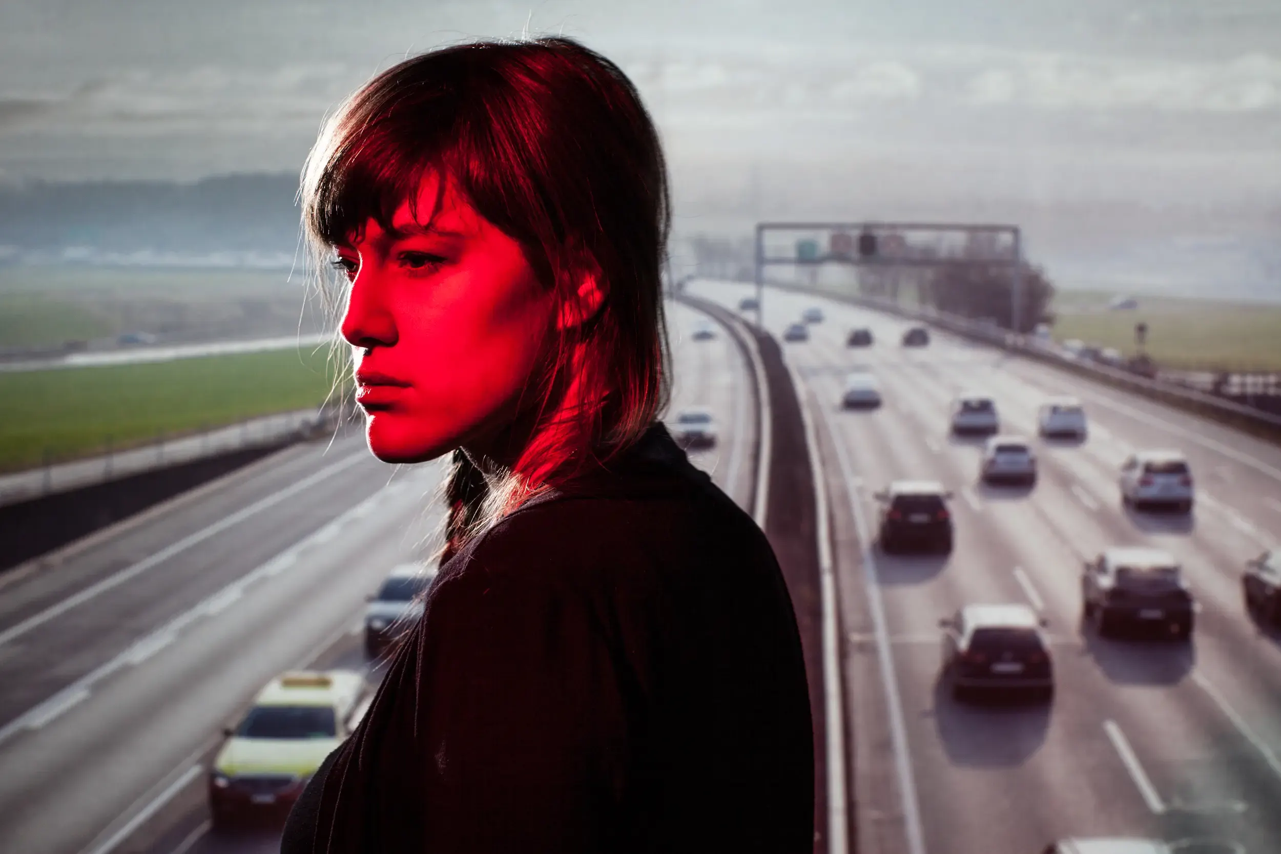Frau vor Autobahnkulisse mit rotem Farbstich, aus dem Projekt „A1 – Ein Stück Schweizer Strasse“
