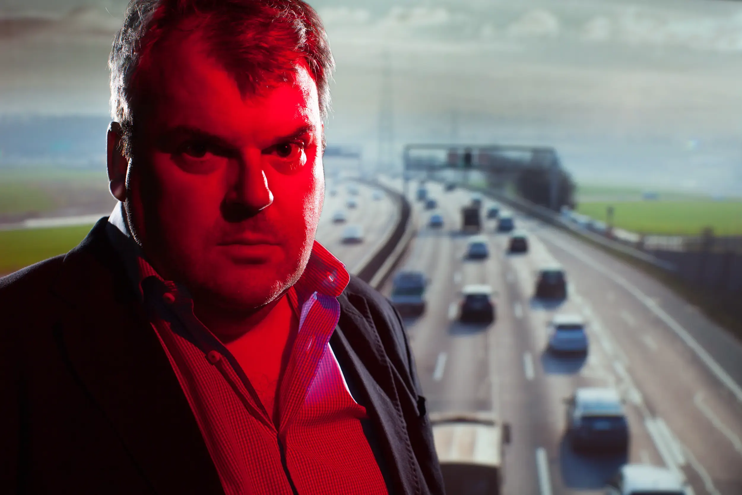 Mann vor Autobahnkulisse mit rotem Farbstich, aus dem Projekt „A1 – Ein Stück Schweizer Strasse“