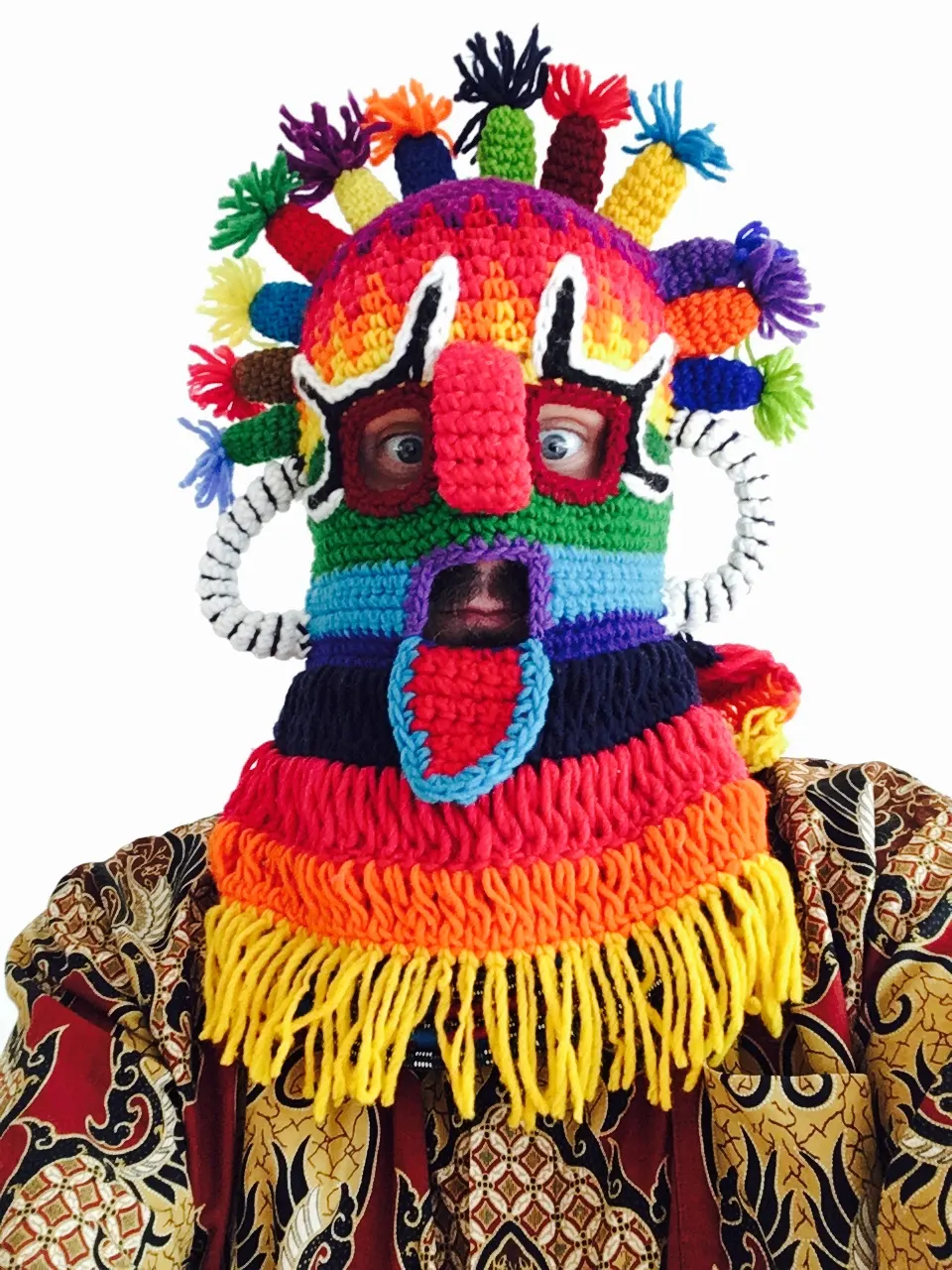 Portrait mit bunter, gehäkelter Maske mit Puschel-Verzierung