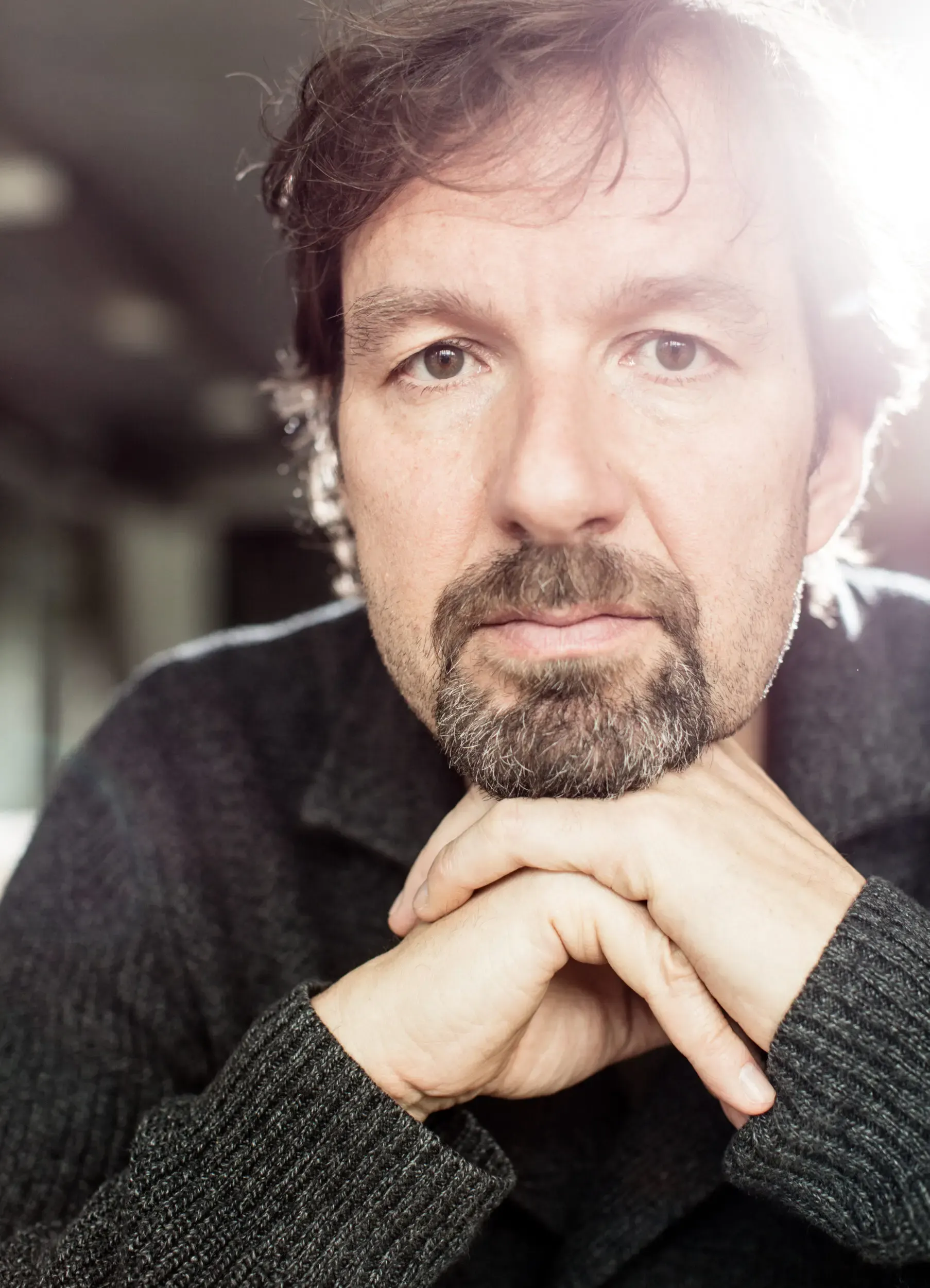 Portrait eines Mannes mit Händen am Kinn vor hellem Hintergrund