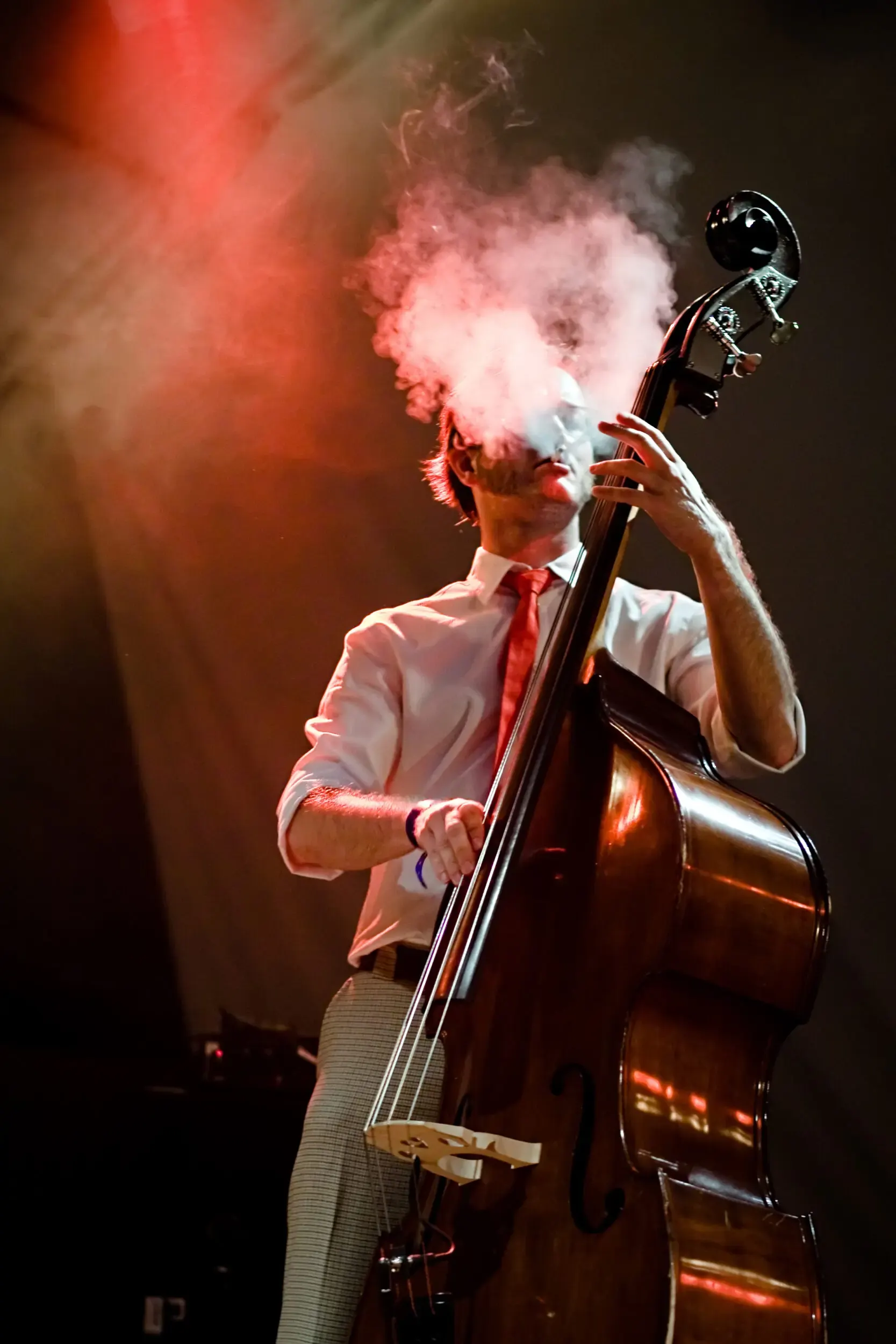 Musiker spielt Kontrabass im roten Bühnenrauch