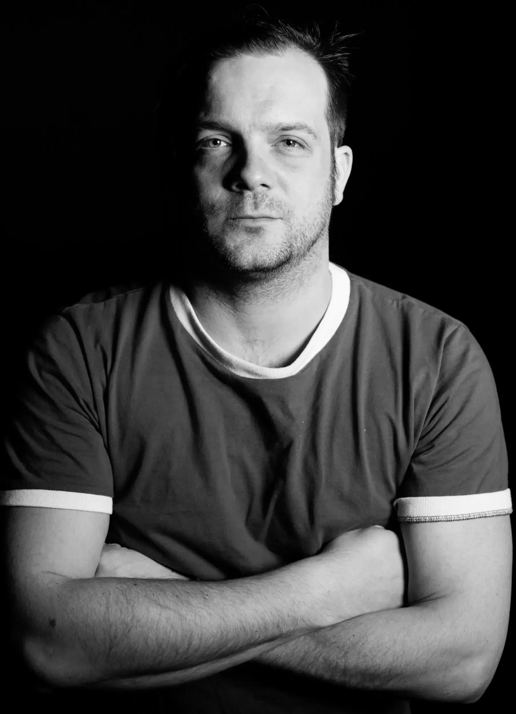 Black-and-white studio portrait of André Willmund with arms crossed against a black background.