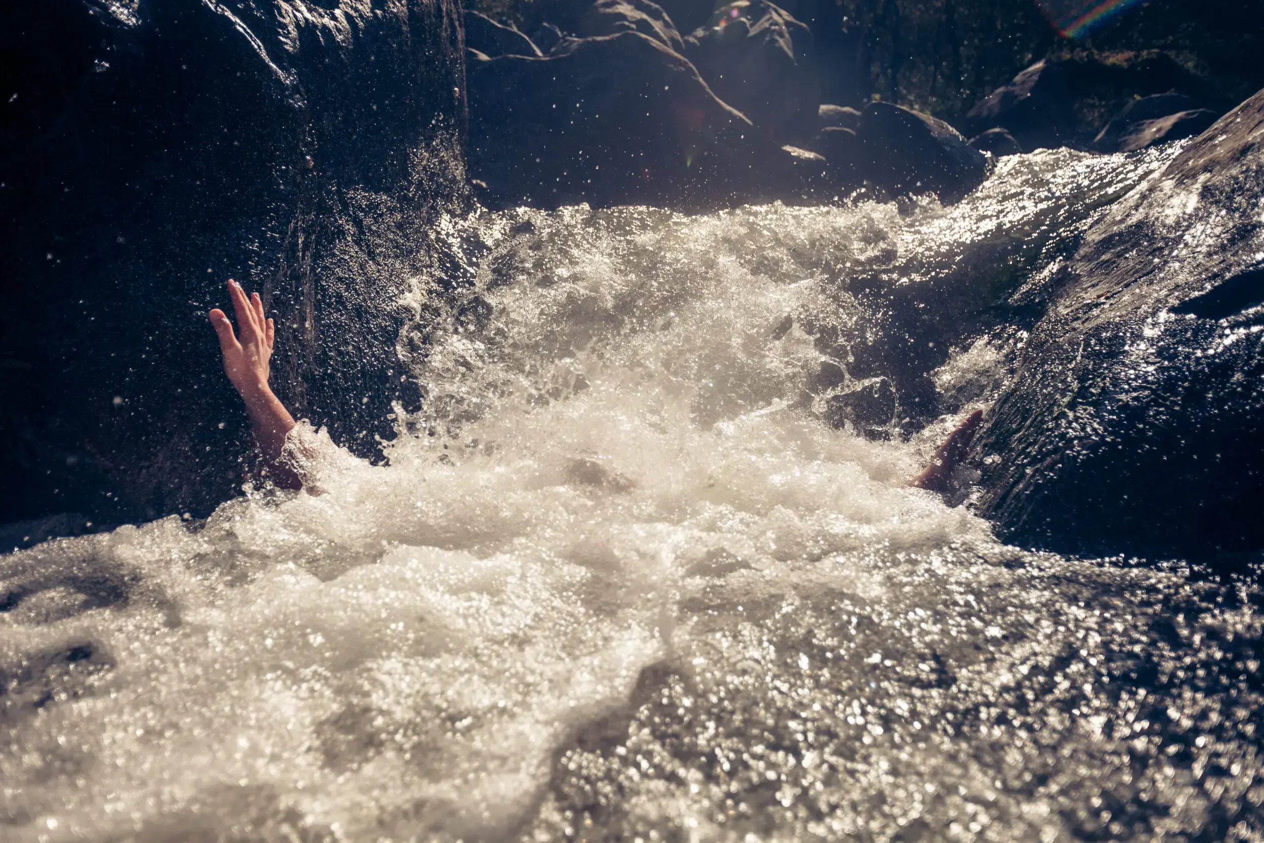 A hand reaching up out of the rushing white water of a waterfall in Argentina.