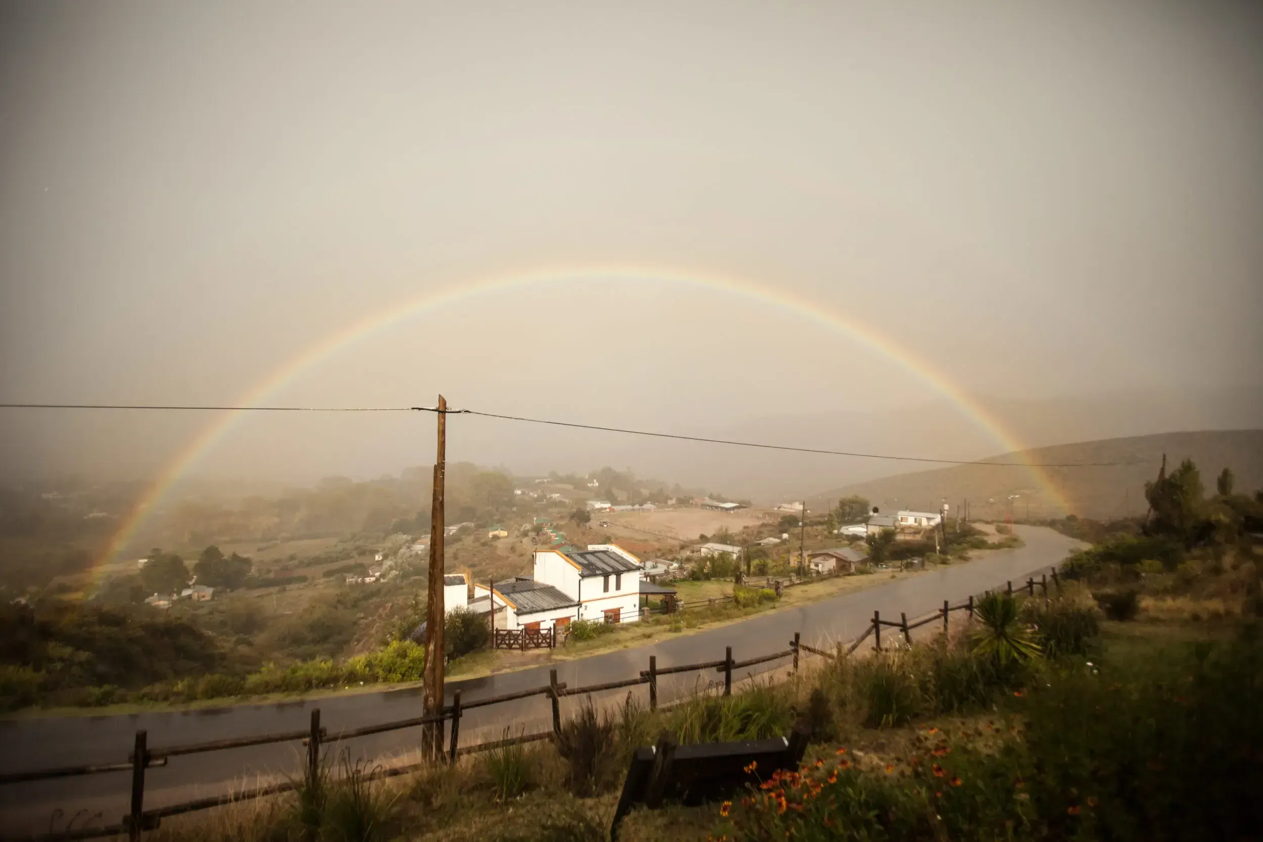 Full rainbow arching over a small mountain village in Argentina after rain.