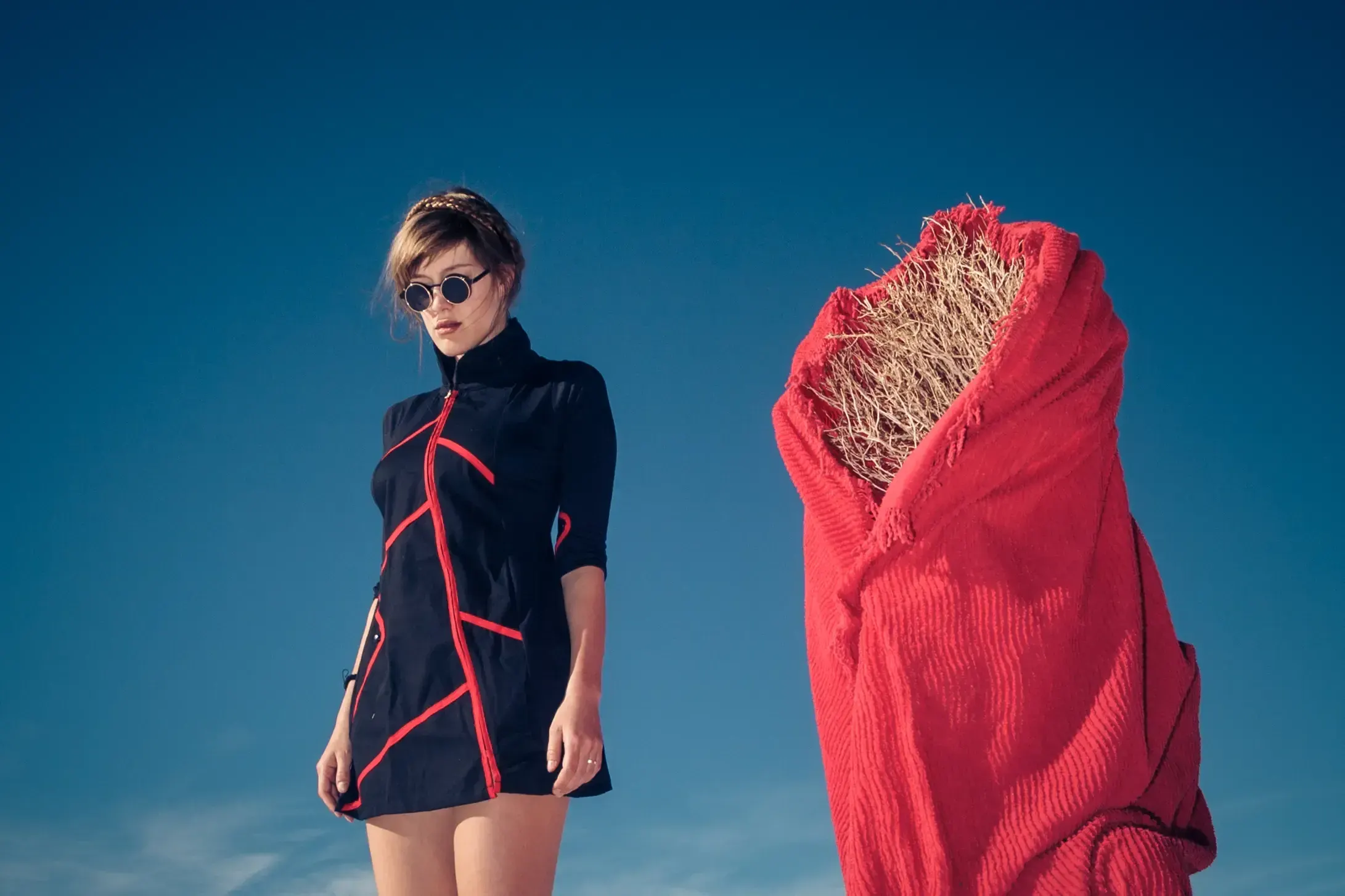 Woman in a black and red dress standing beside a red fabric bundle on the salt flats of Argentina.