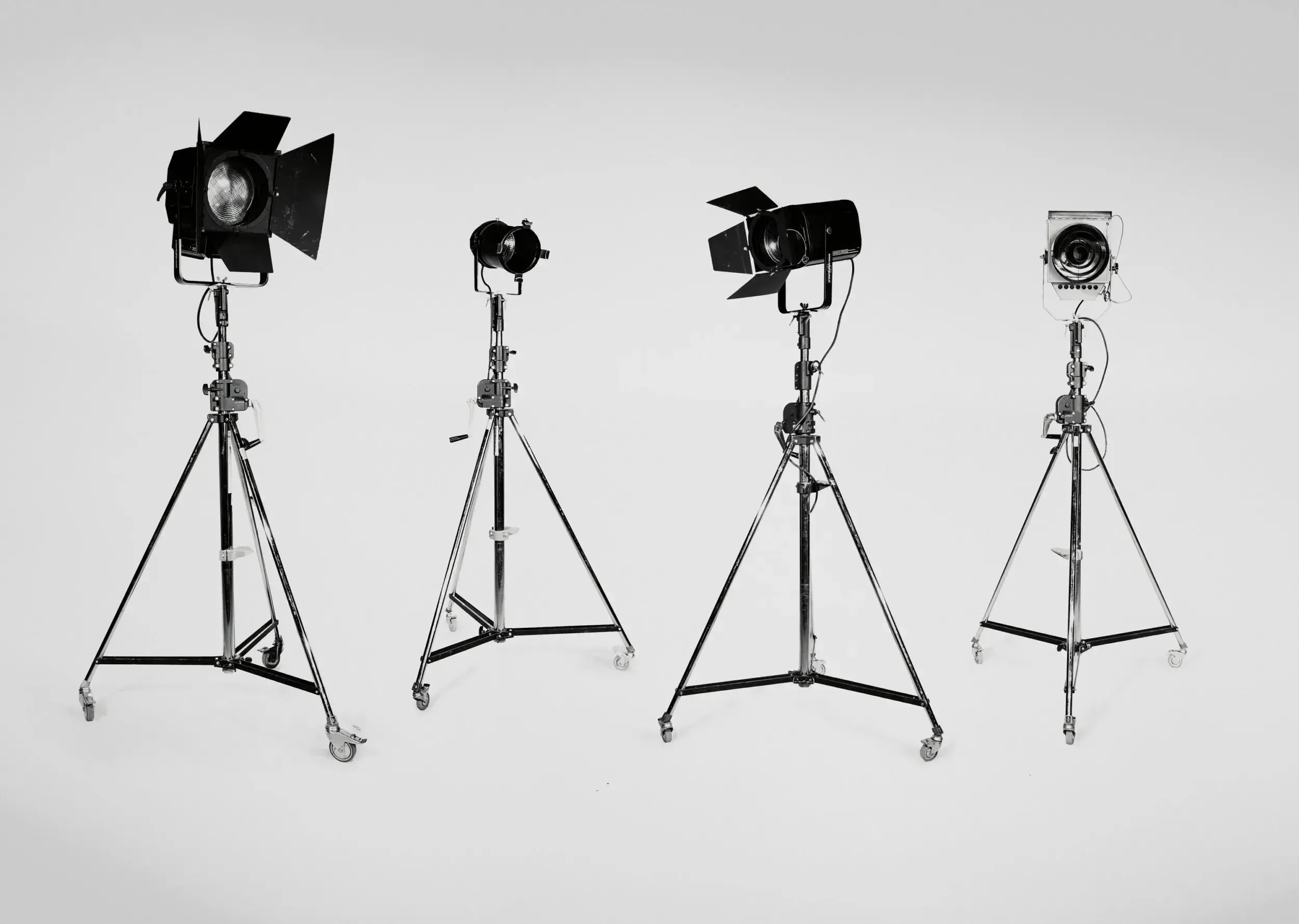 Four vintage stage lights on tripod stands lined up like a band photo.