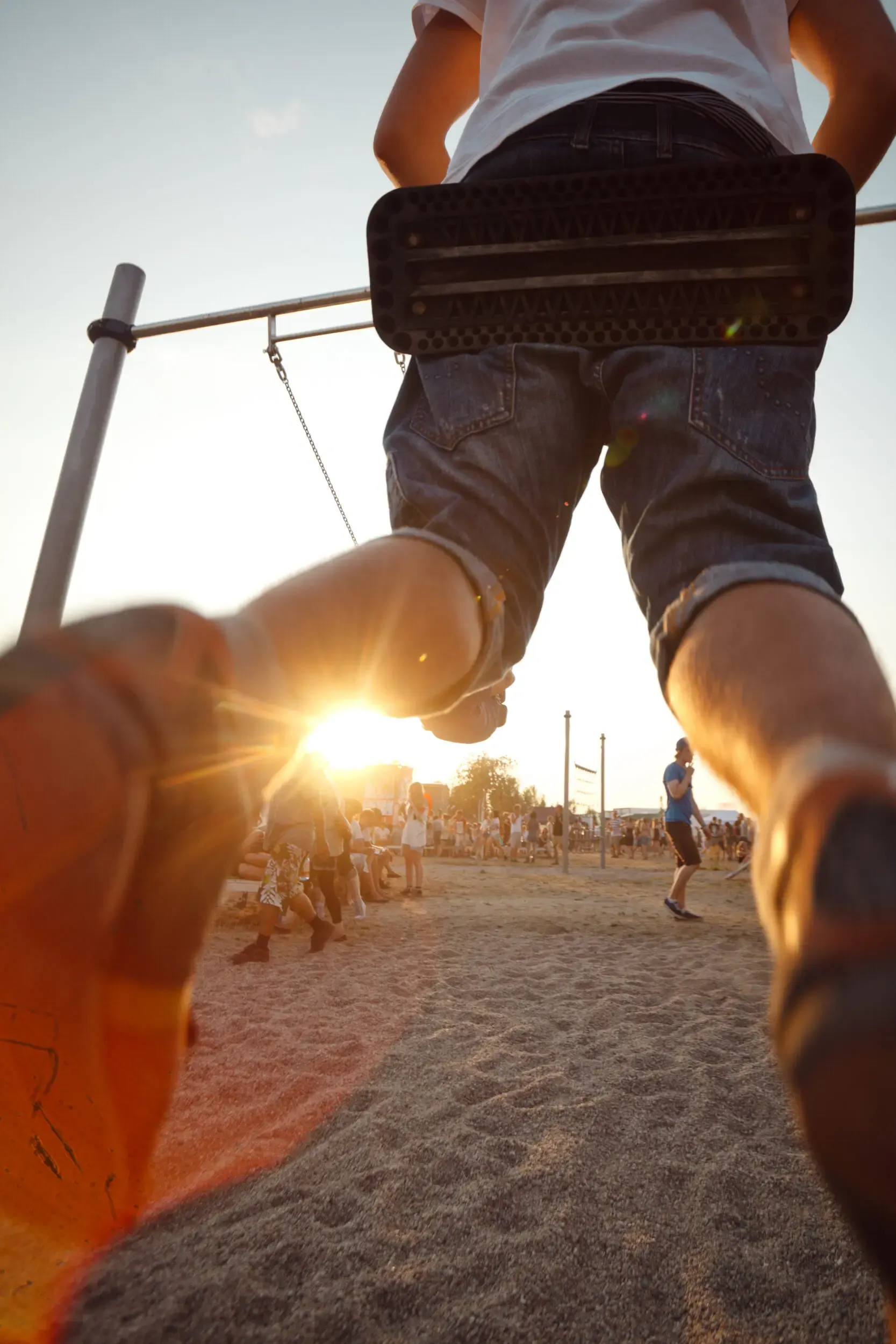 Person schwingt an einer Seilschaukel am Strand im Sonnenuntergang