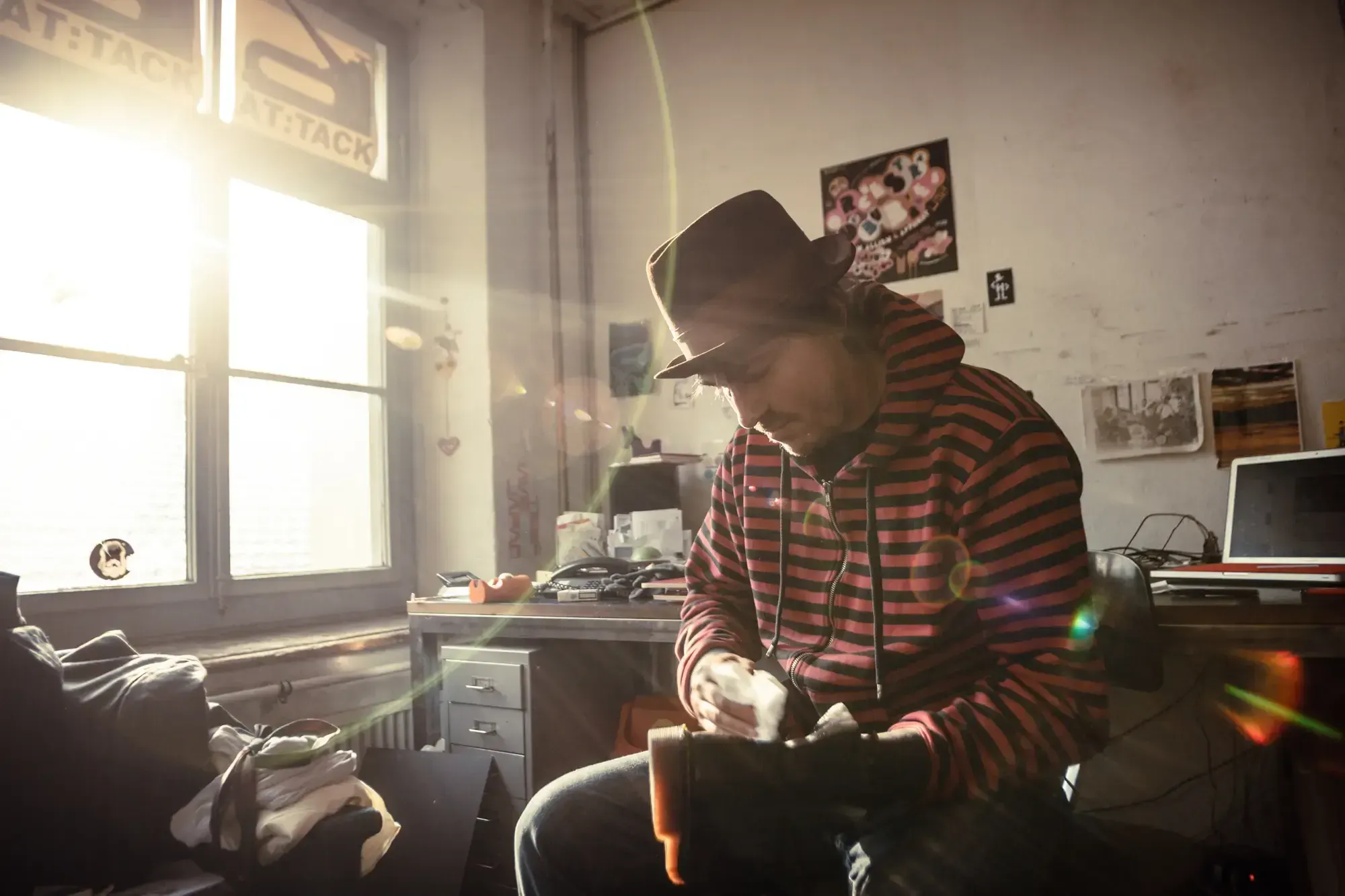 Designer wearing a hat working at a sunlit desk inside the Büro Destruct studio.