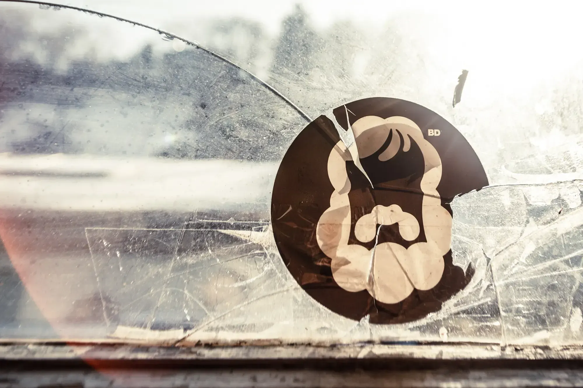 Büro Destruct logo sticker on a cracked, frosted car window.