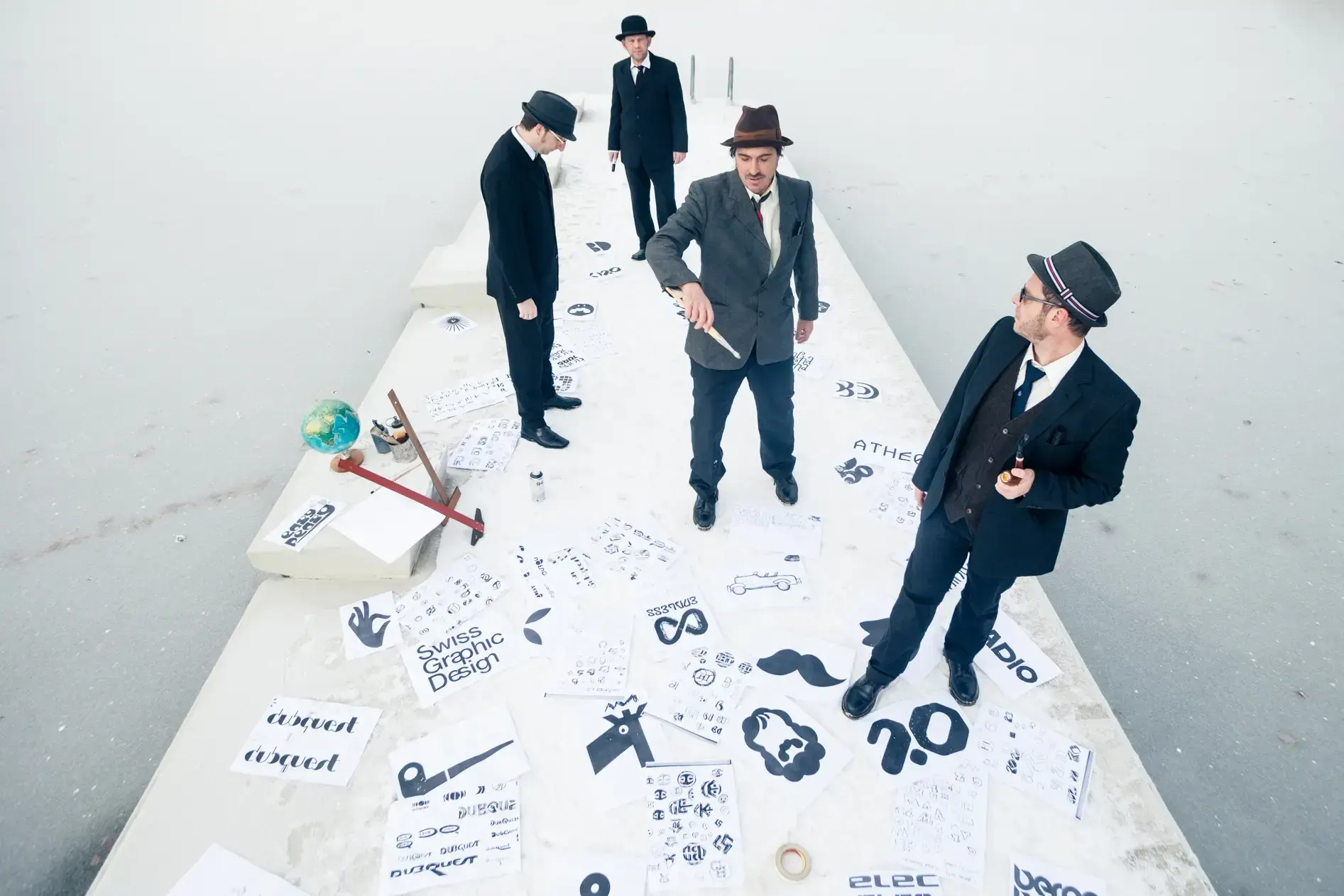 Aerial view of the Büro Destruct team standing around logo sketches spread across a rooftop.