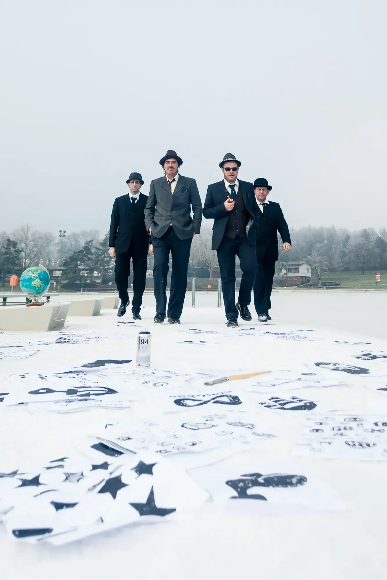 The Büro Destruct team walking together across a rooftop covered in logo sketches and a globe.