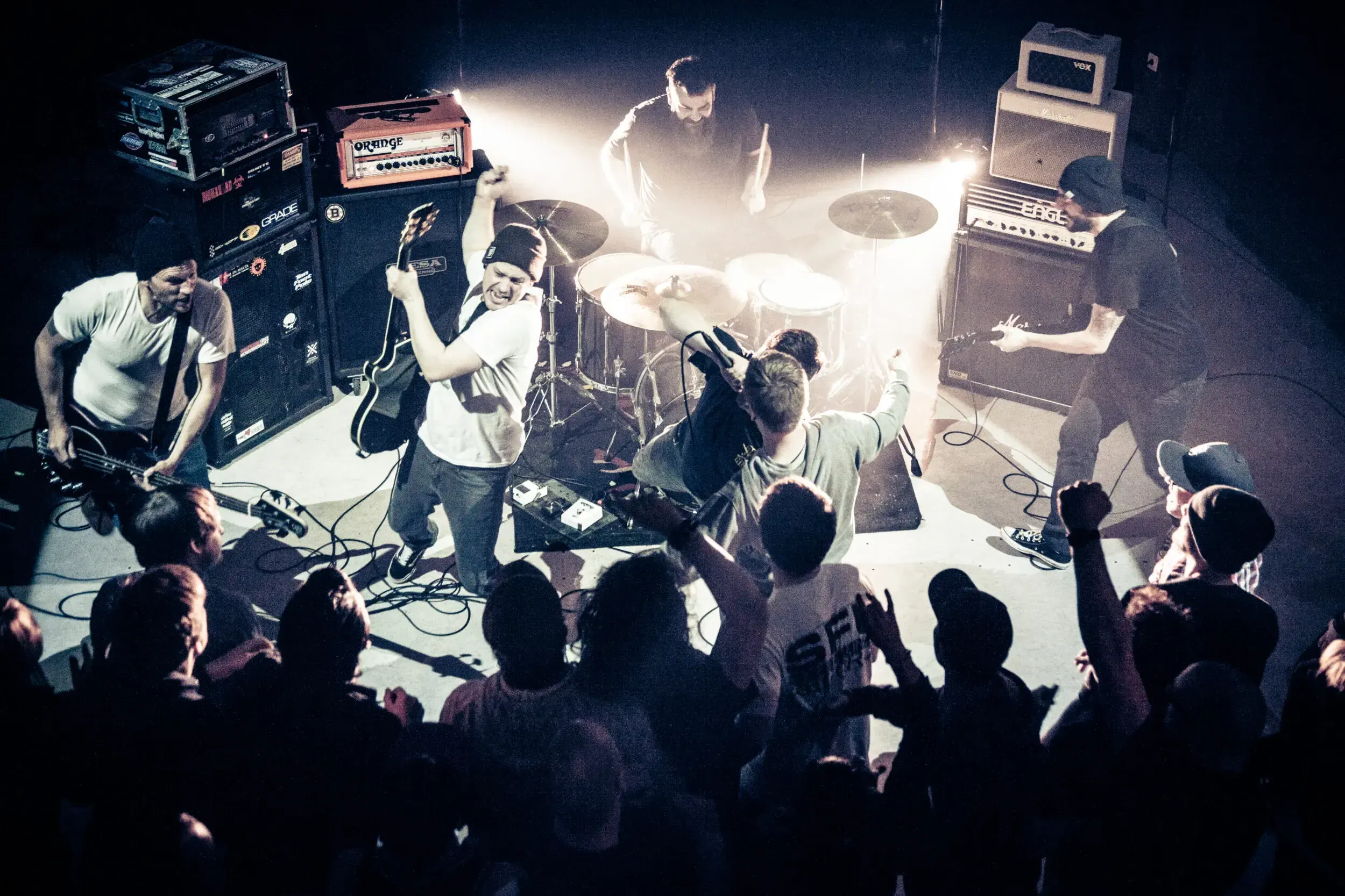 Overhead view of the band Chelsea Deadbeat Combo performing on stage above a cheering crowd.