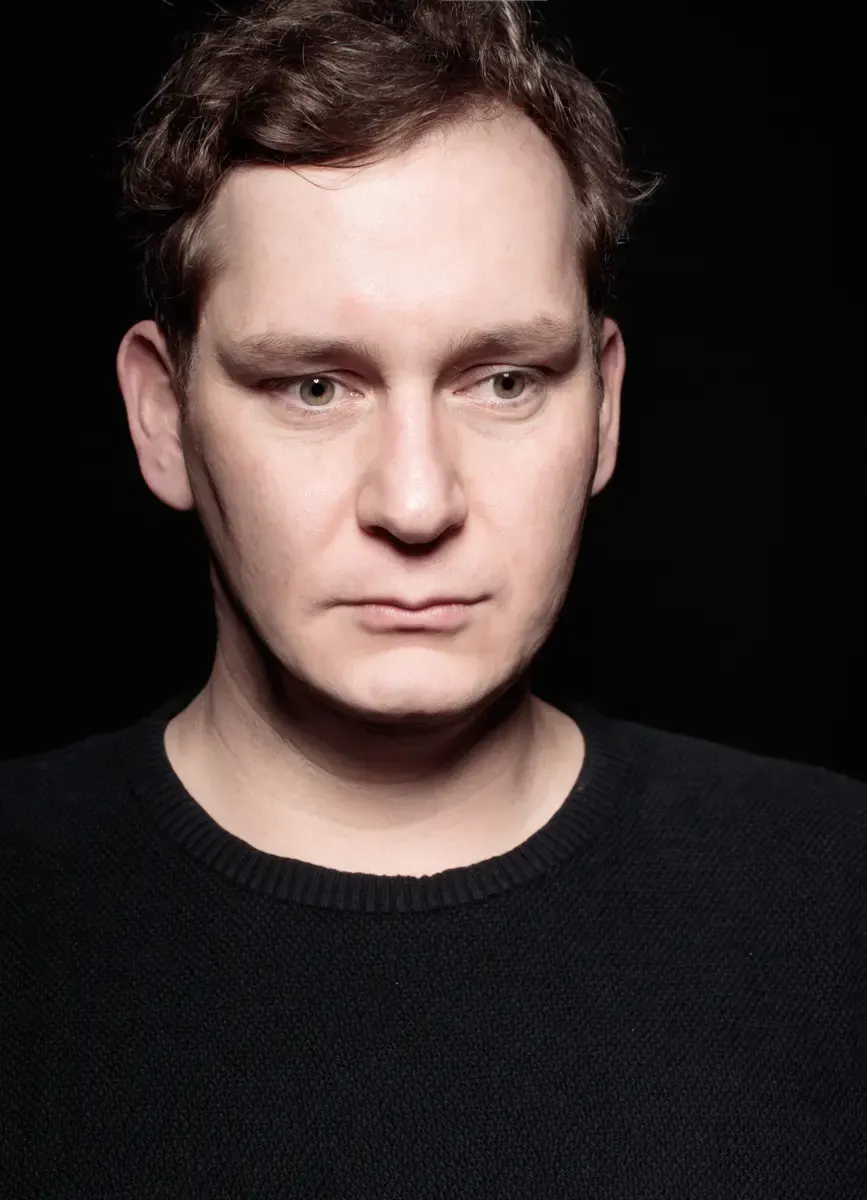 Nahaufnahme-Portrait von Christian Baumbach vor dunklem Hintergrund