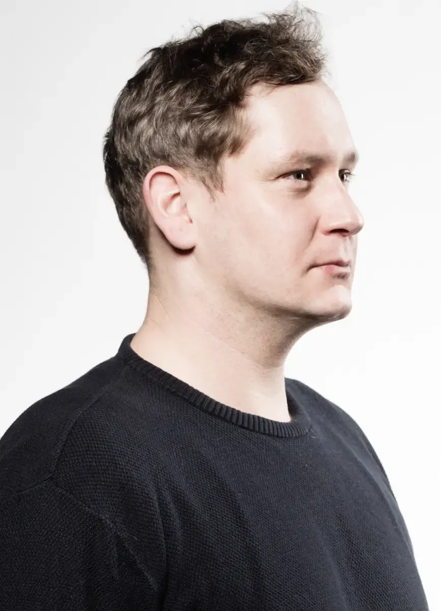 Portraitfoto von Christian Baumbach in schwarzem Pullover vor hellem Hintergrund