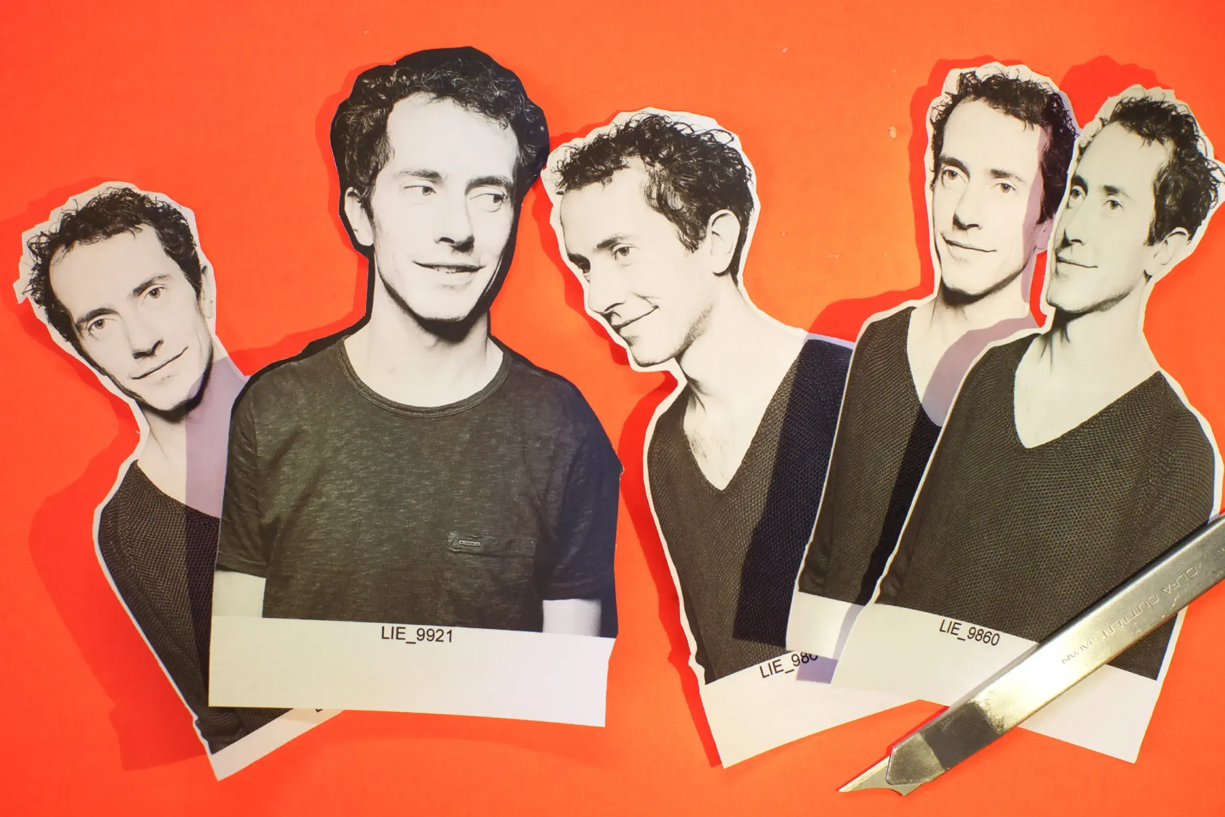 Cut-out paper portraits of a man's face arranged for a stop-motion animation, with a craft knife beside them.