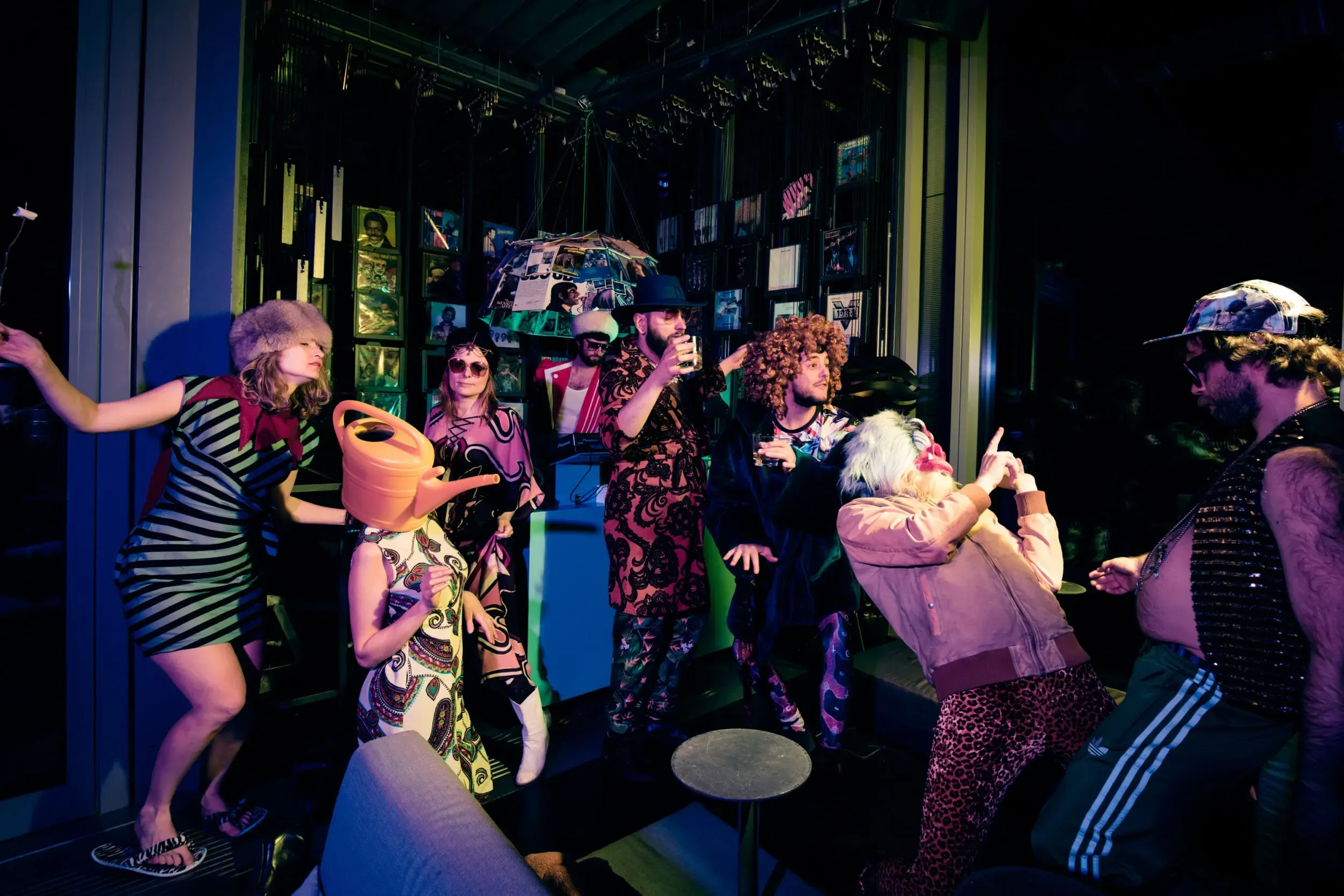 Costumed guests dancing in a dimly lit, colourfully gelled bar.
