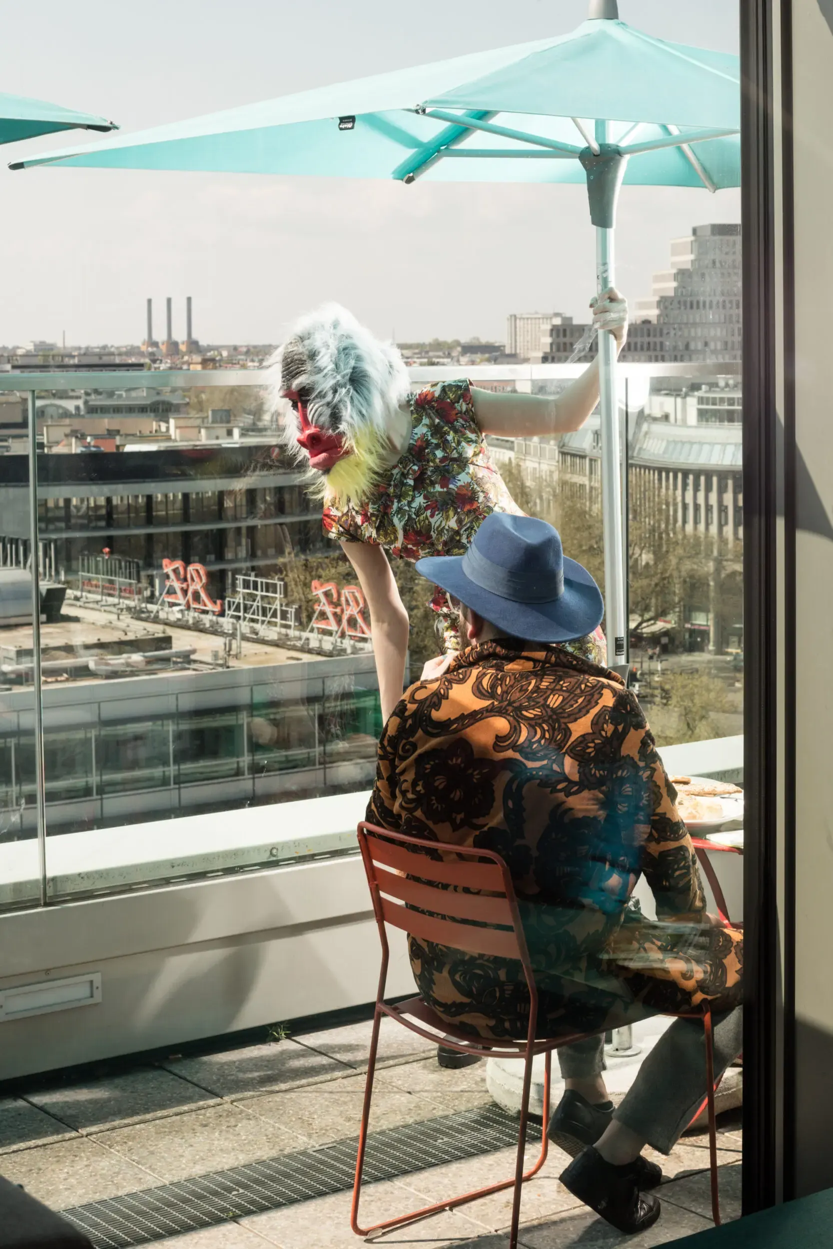 Guest in a fur hat seated by a window overlooking the city skyline.