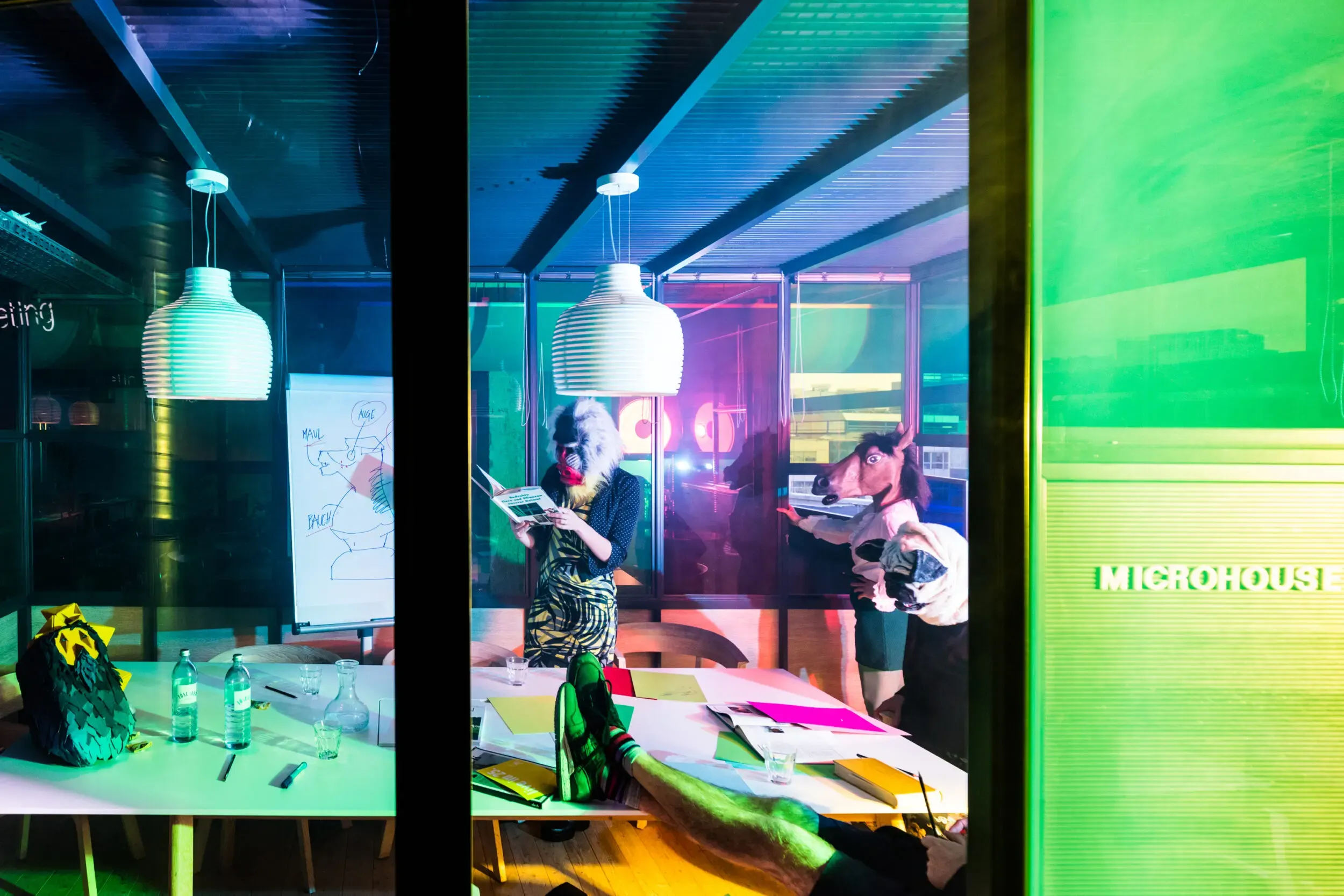 Costumed guests in an office under green lighting, captured with motion blur.