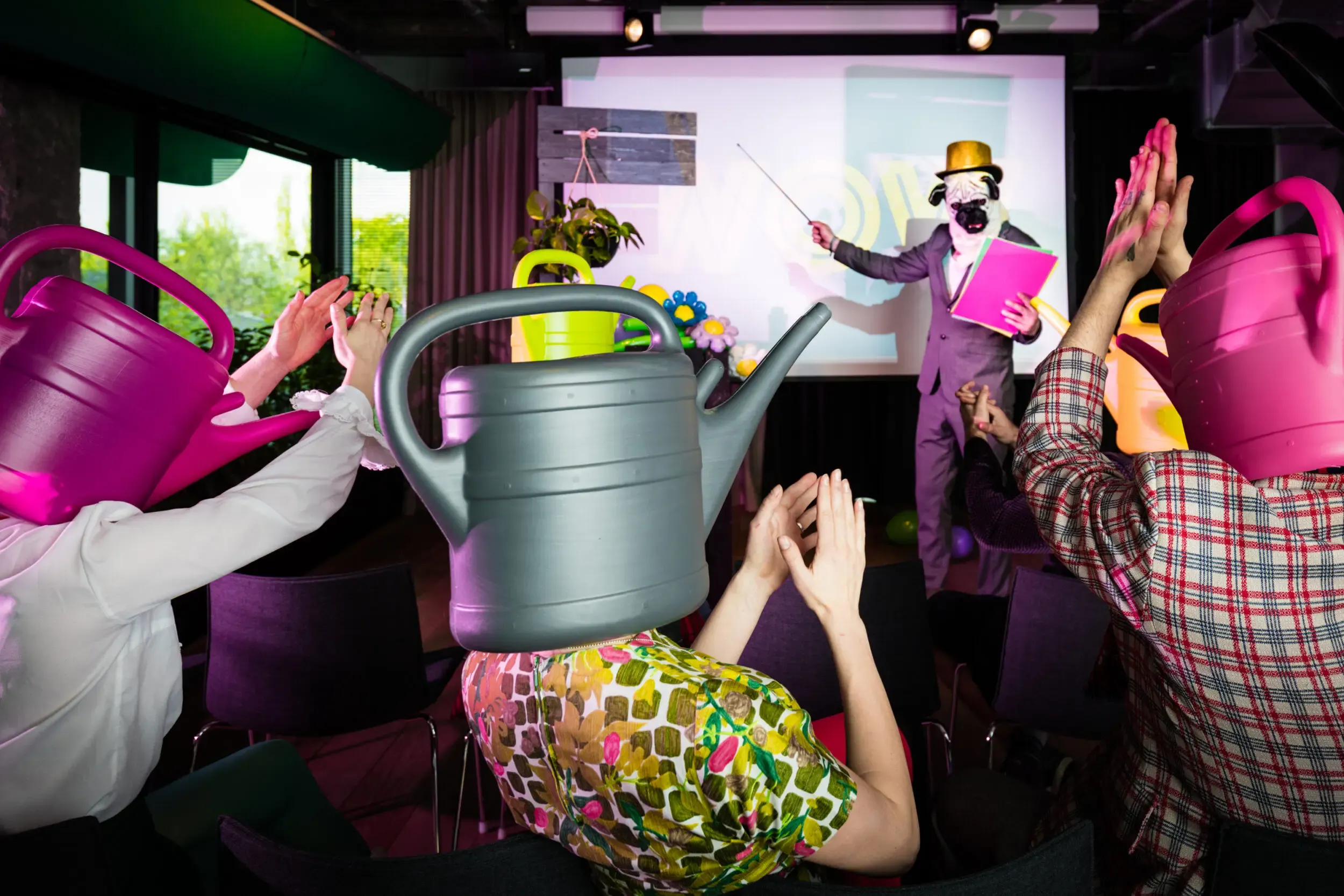 Costumed guests raising their arms together, one wearing a pink watering-can mask.