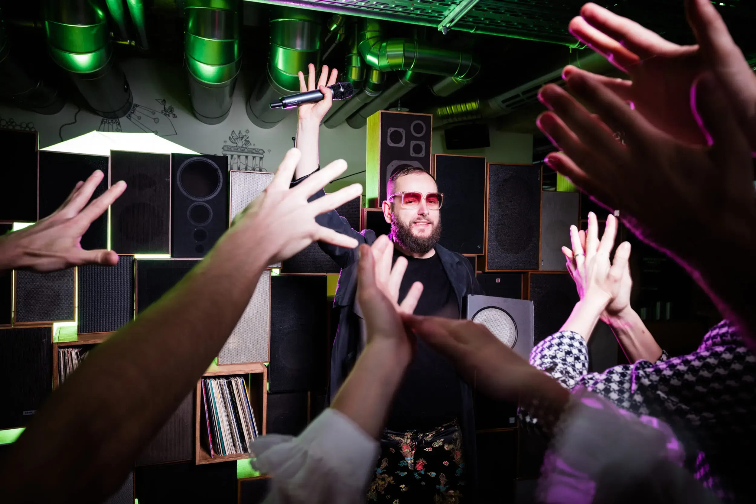 Costumed guests silhouetted with hands raised near music equipment.