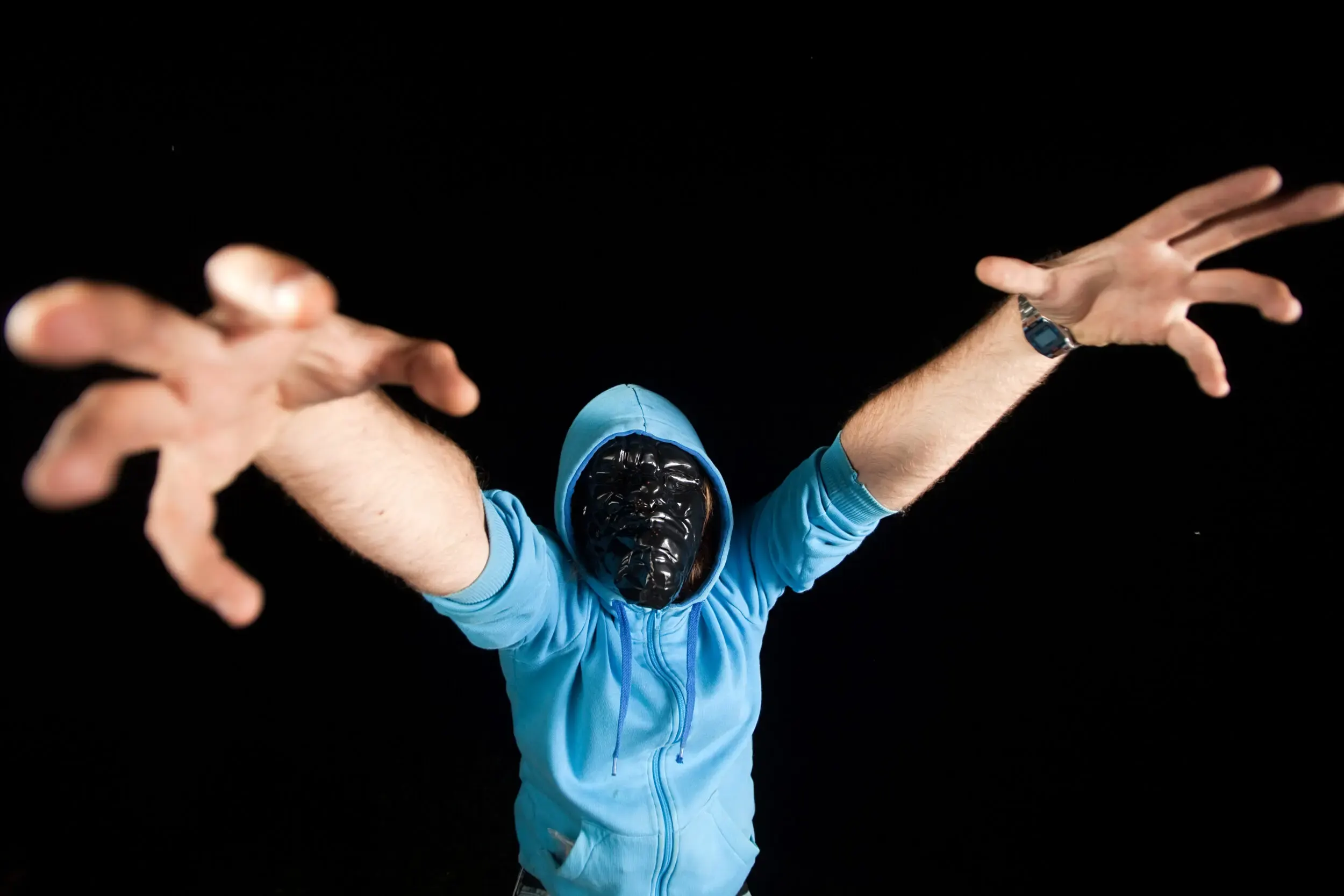 Person mit Maske streckt die Hände zur Kamera, Cross Section