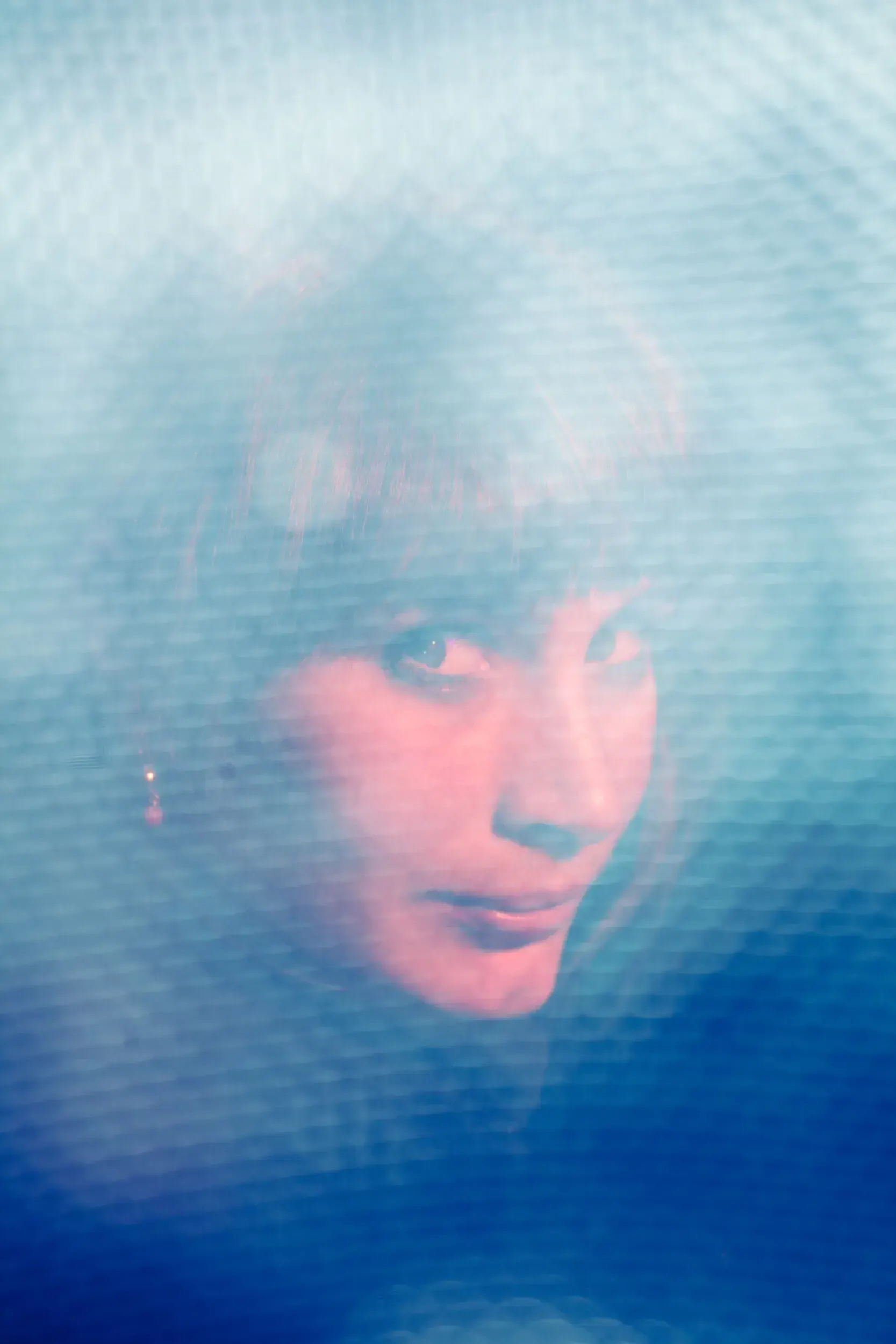 Portrait of Dagna Litzenberger Vinet seen through a blue-lit semi-transparent veil.