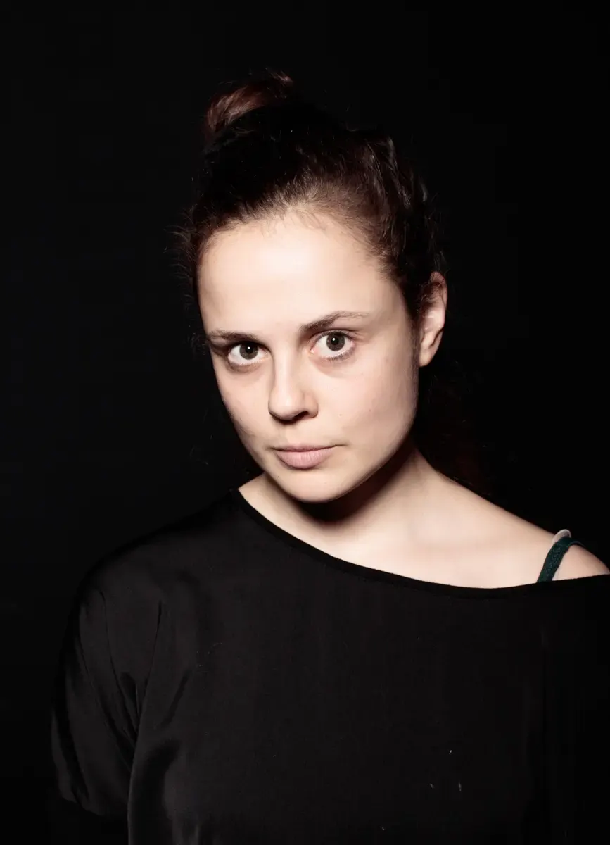 Portraitfoto von Elisa Plüss vor dunklem Hintergrund