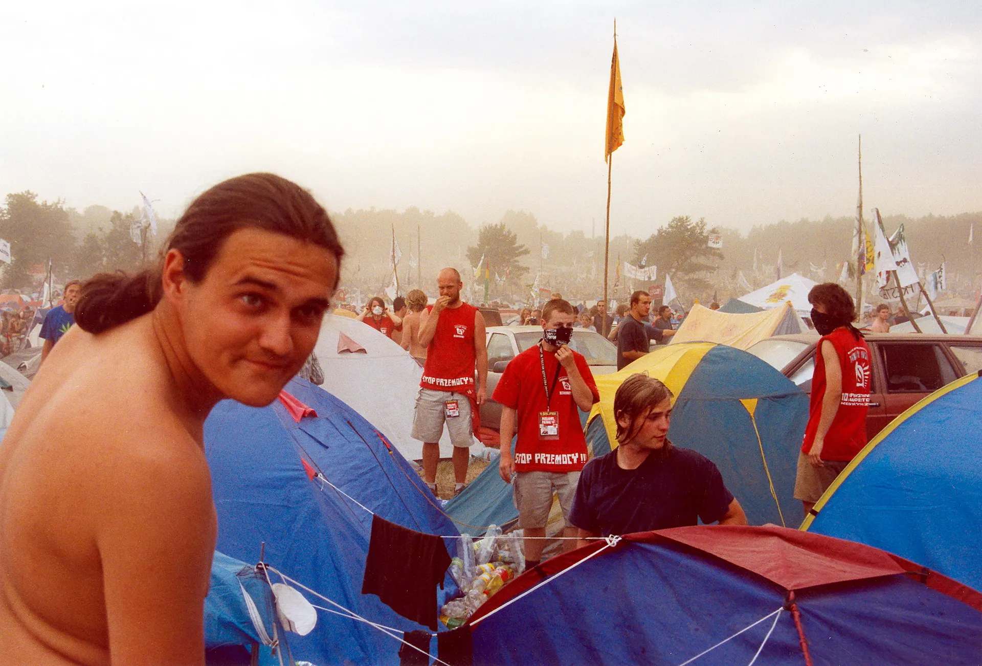 Festivalbesucher sitzt lächelnd zwischen Zelten