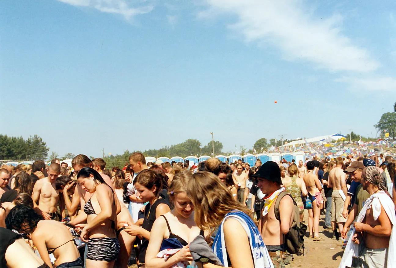 Festivalbesucher sitzen auf dem weiten Festivalgelände