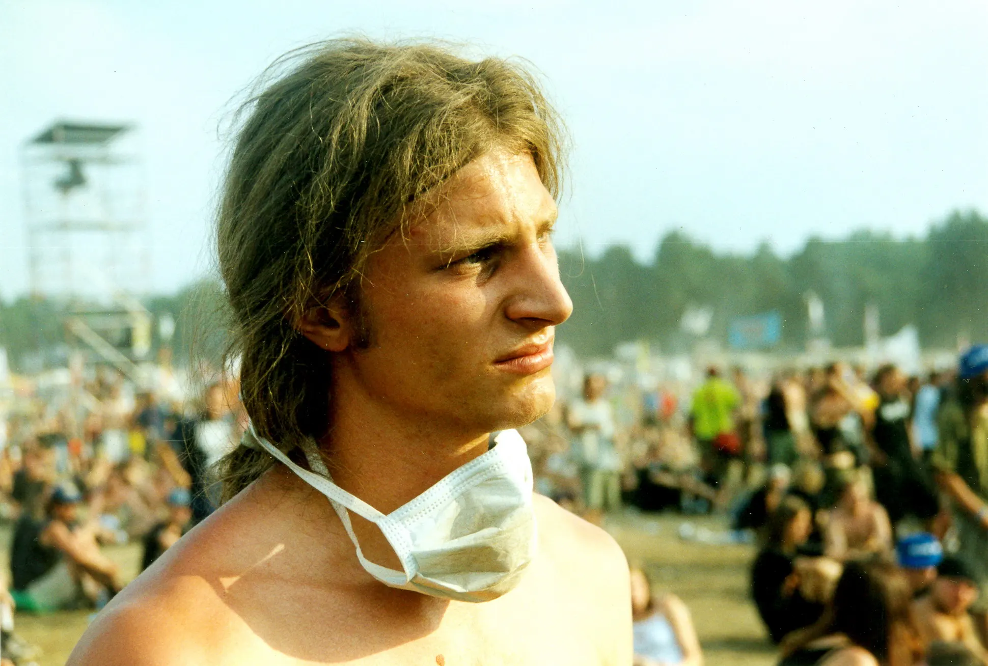 Festivalbesucher mit staubverschmiertem Gesicht und Mundschutz um den Hals