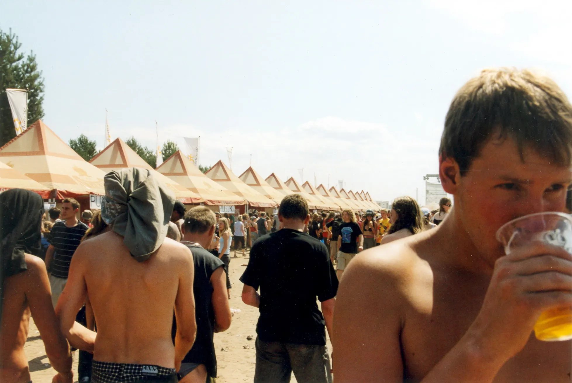 Junger Festivalbesucher trinkt Bier inmitten der Menge