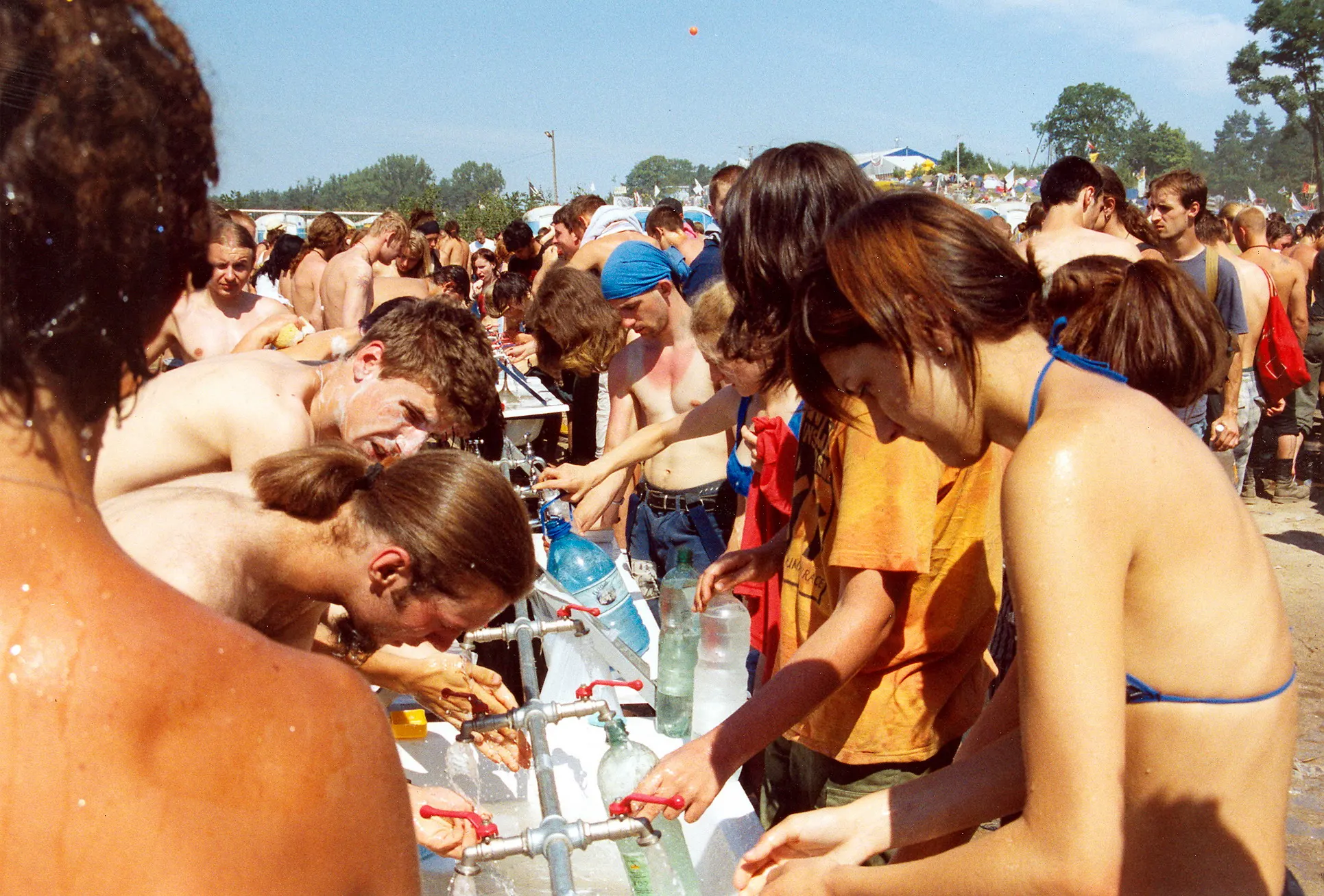 Festivalbesucher waschen sich gemeinsam an einer langen Wasserrinne