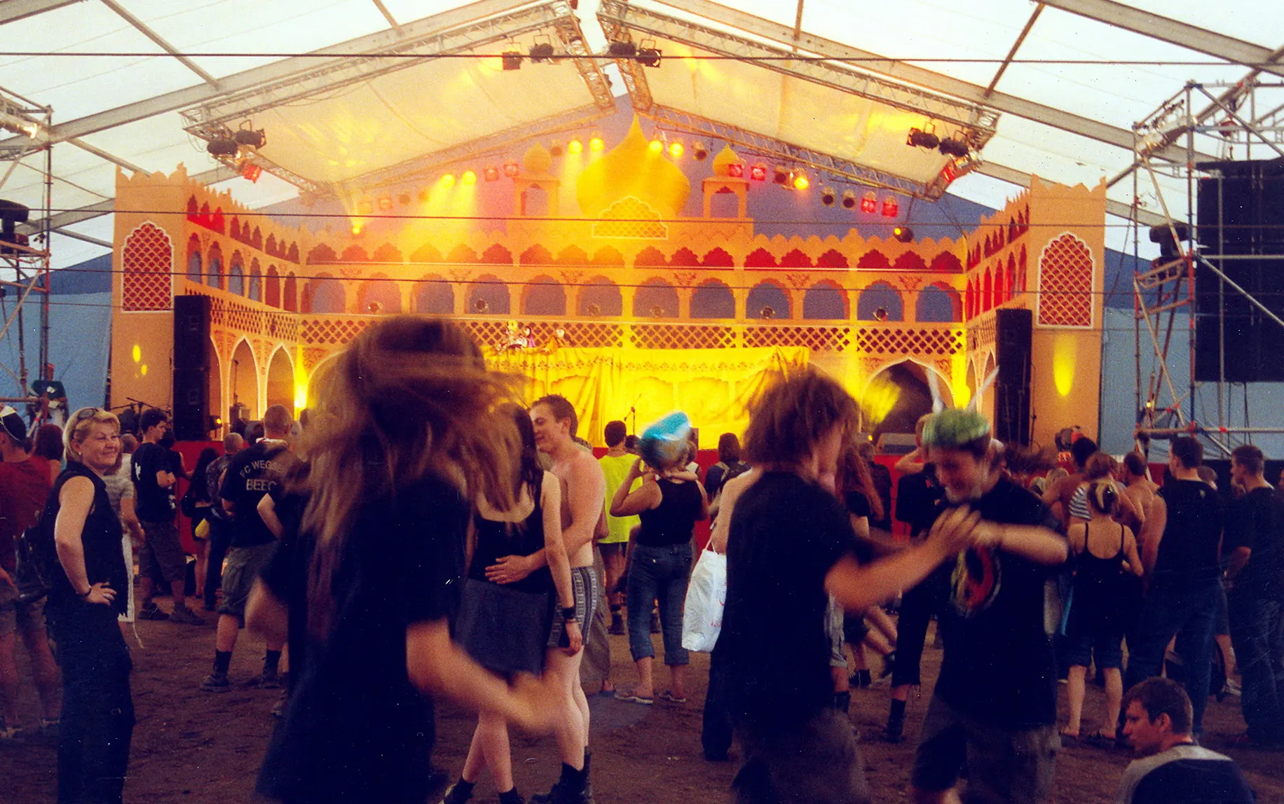 Bunt beleuchtetes Bühnenzelt mit tanzenden Besuchern bei Nacht