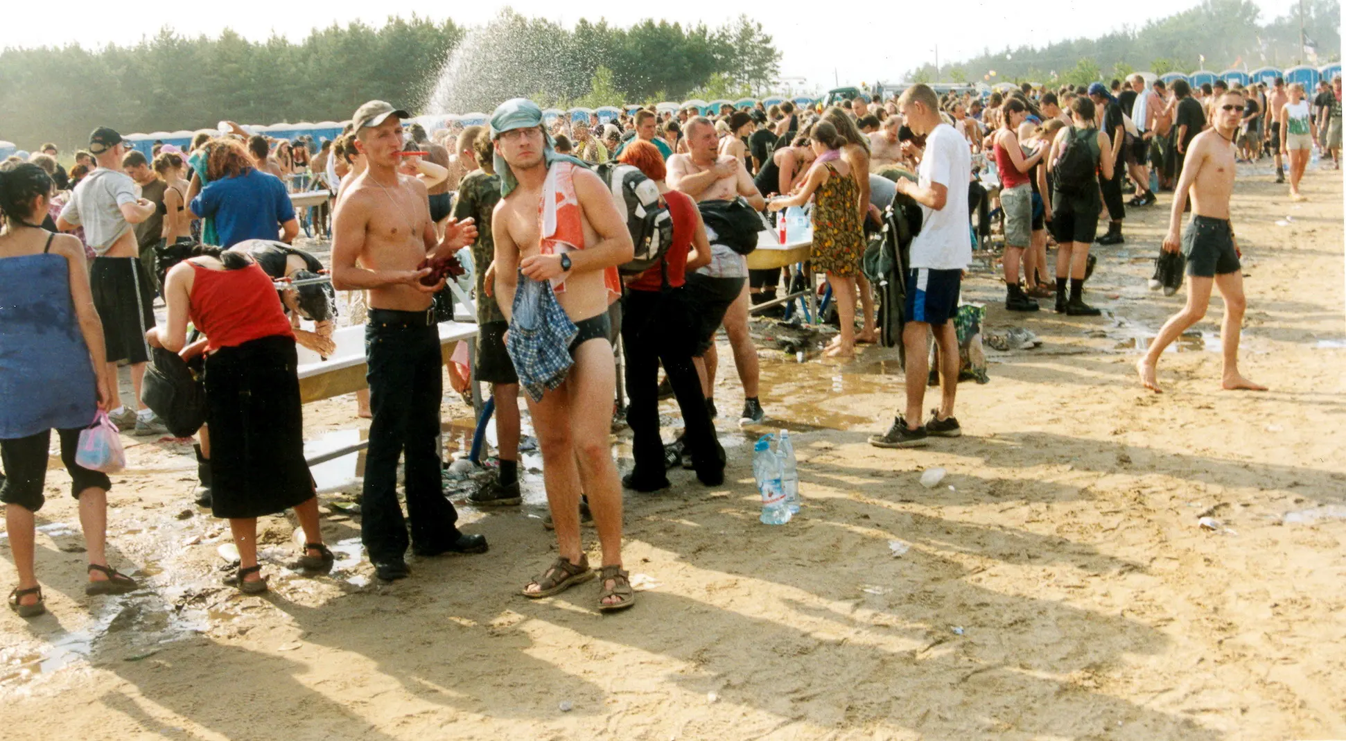 Festivalbesucher stehen an einer Wasserstelle im Staub