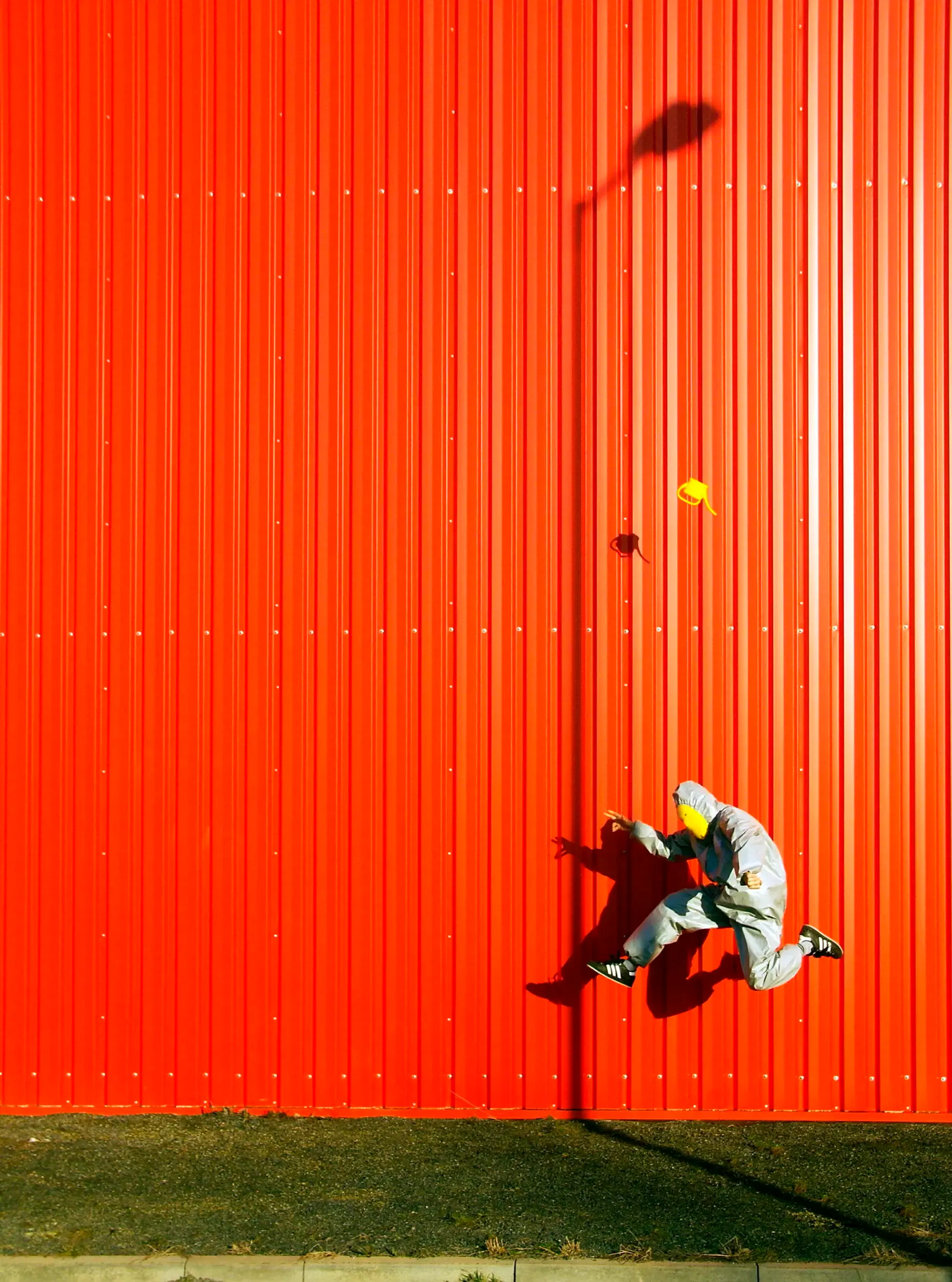 Person springt vor leuchtend orangefarbener Wand