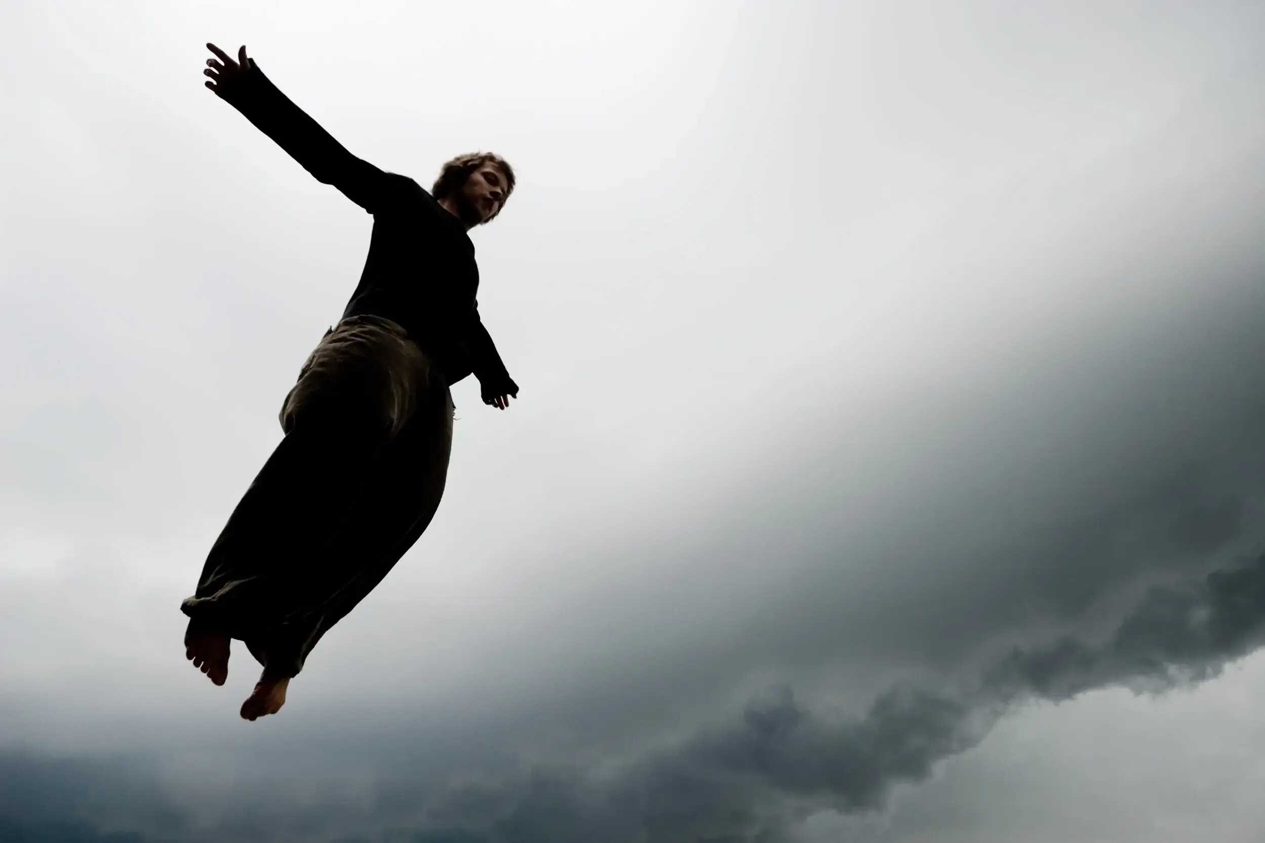 Silhouette einer springenden Person vor stürmischem Himmel