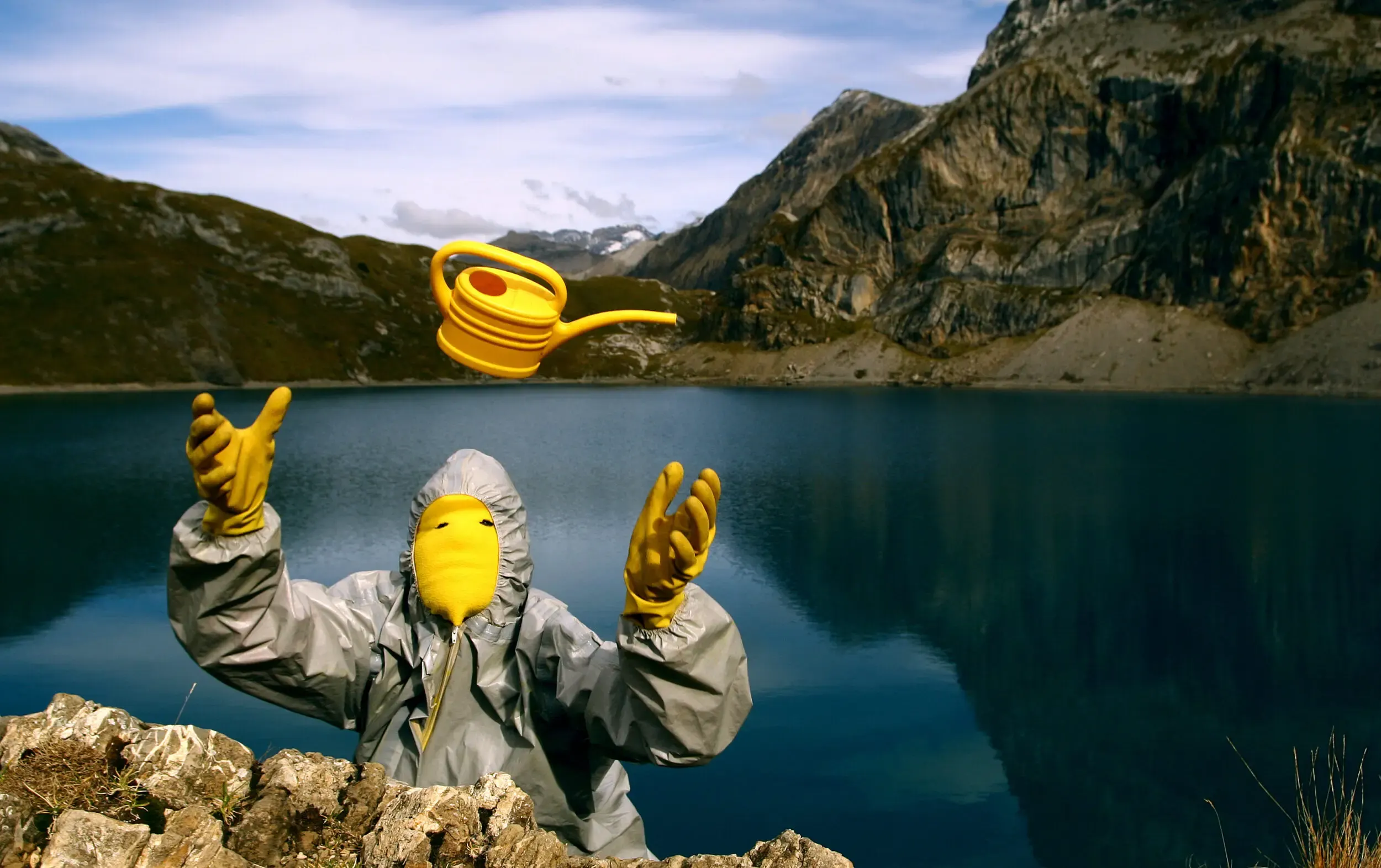 Person im Schutzanzug fängt einen Gegenstand an einem Bergsee, graugelb™