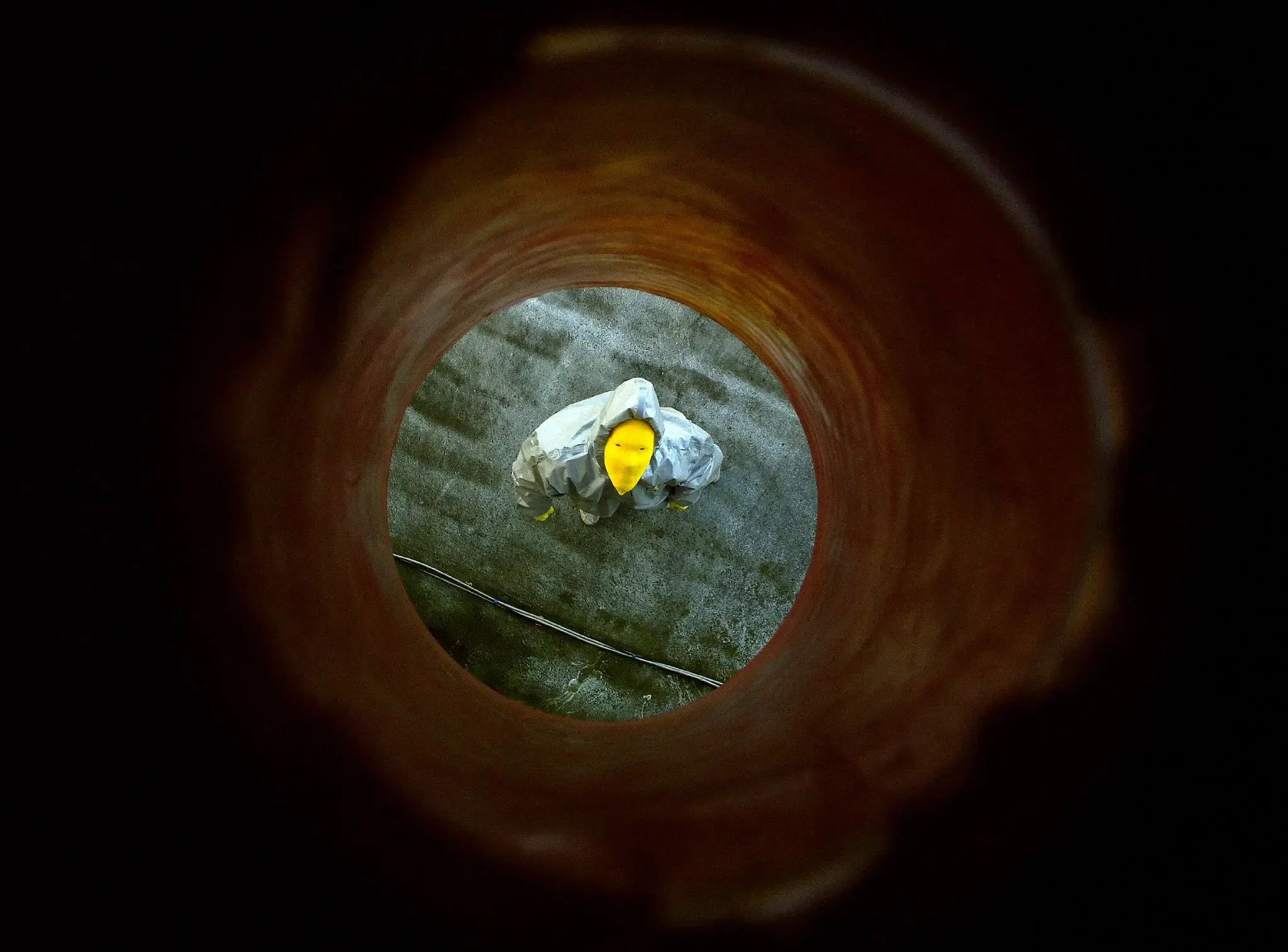 Person im grau-gelben Schutzanzug in einem Rohrtunnel, graugelb™