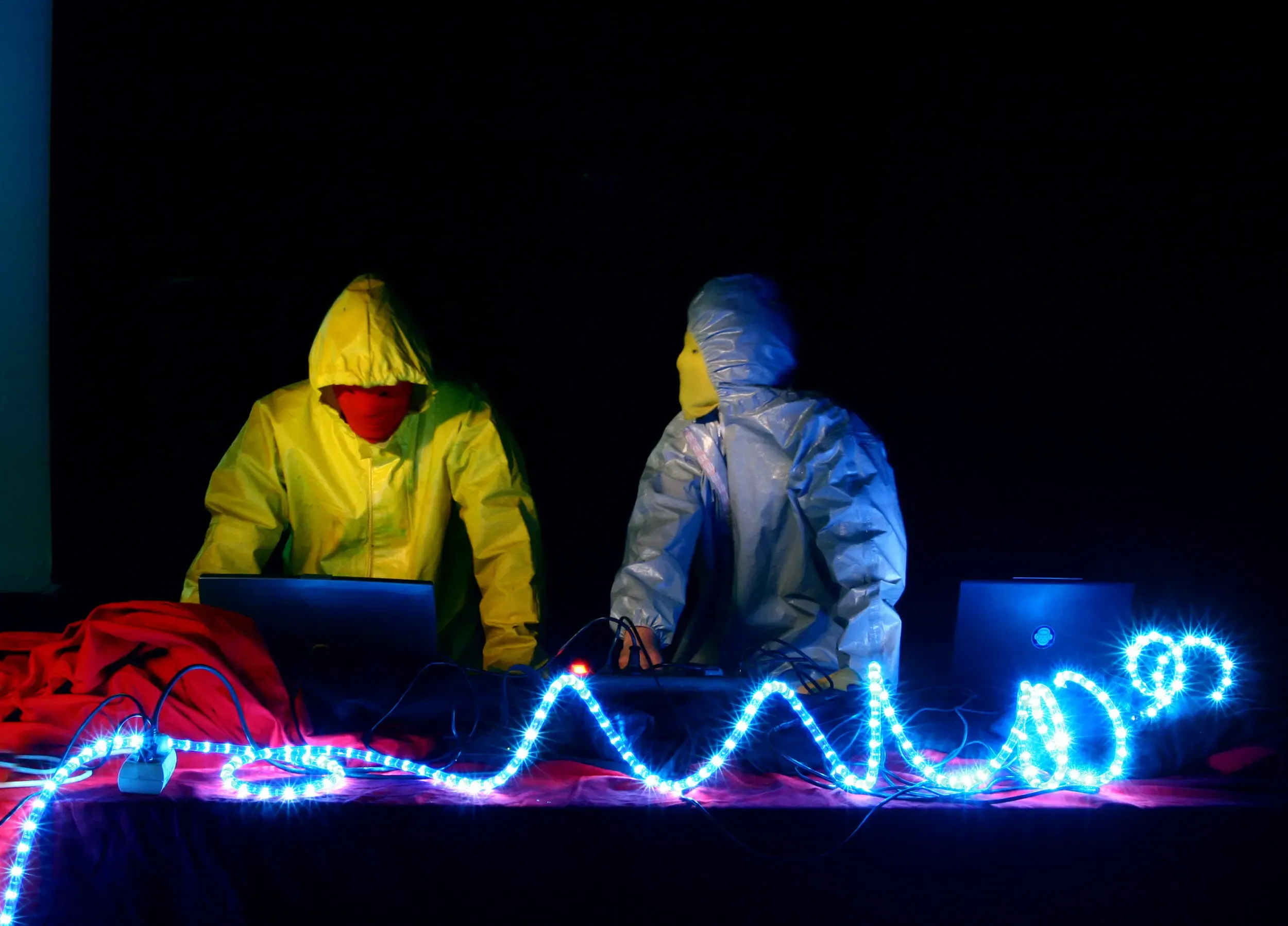 Zwei Personen im Schutzanzug mit leuchtendem Lichterkabel bei Nacht, graugelb™