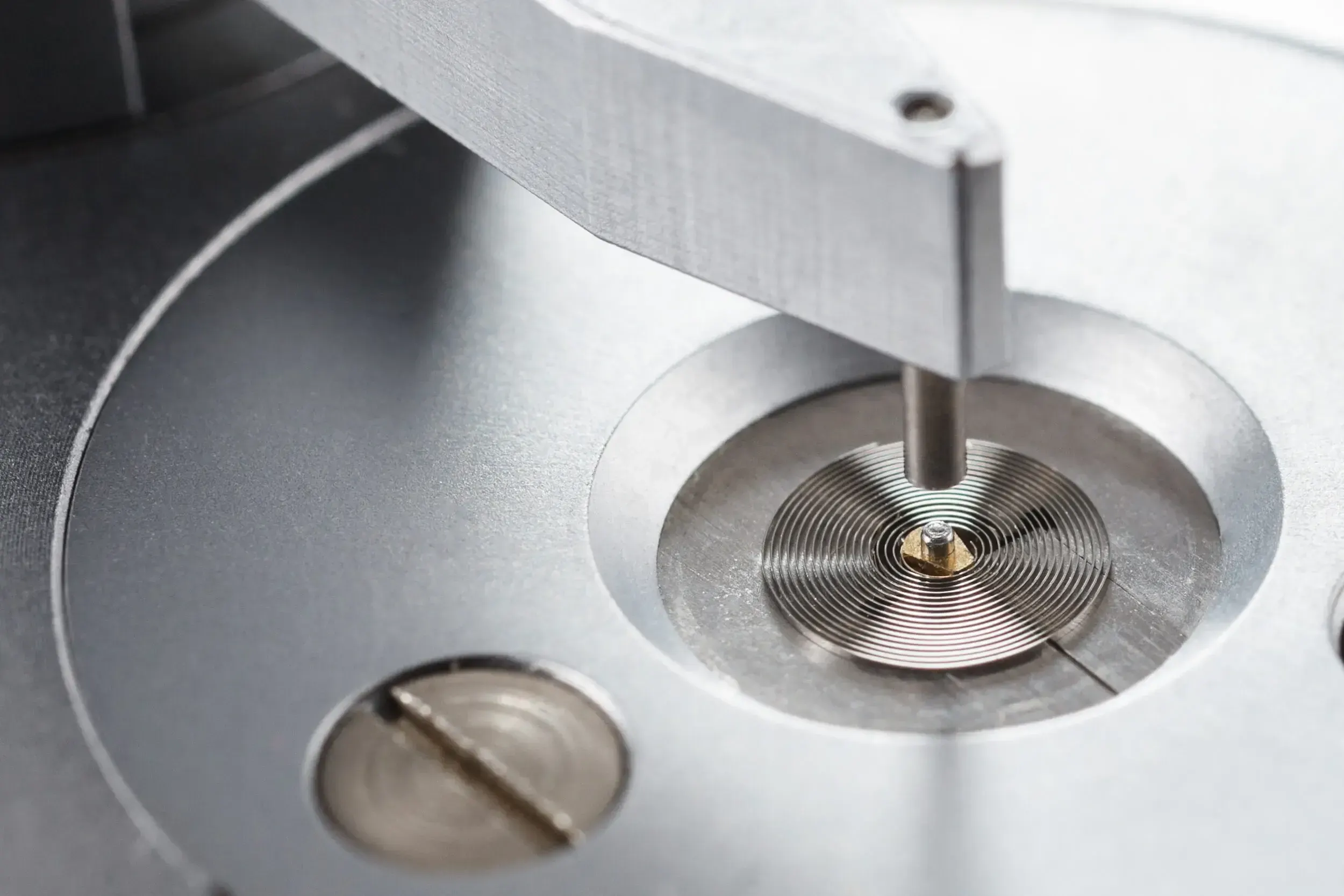 Close-up of a watch balance wheel and hairspring on a precision tool at Greiner Vibrograf.