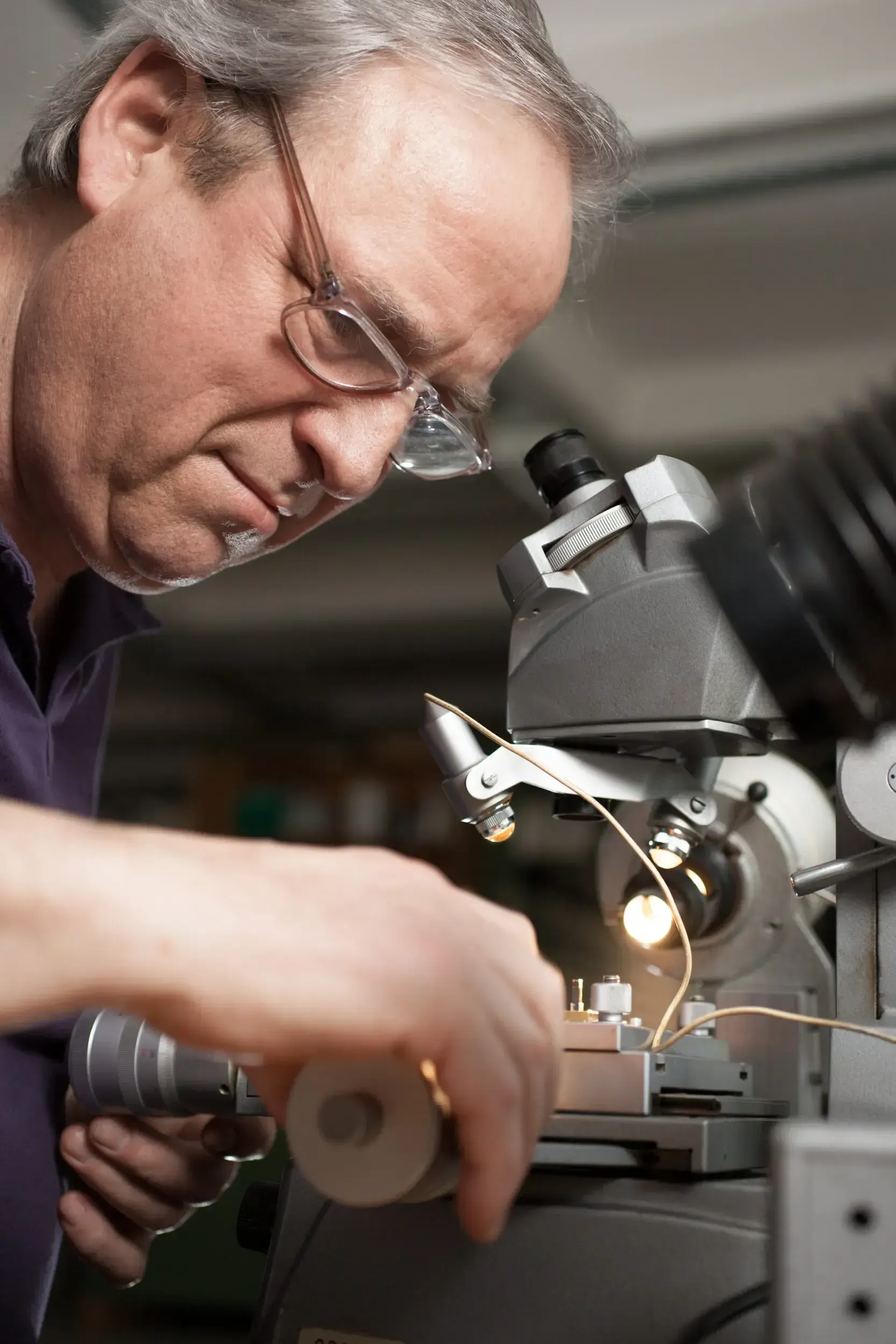 Watchmaker looking through a microscope while adjusting a component at Greiner Vibrograf.