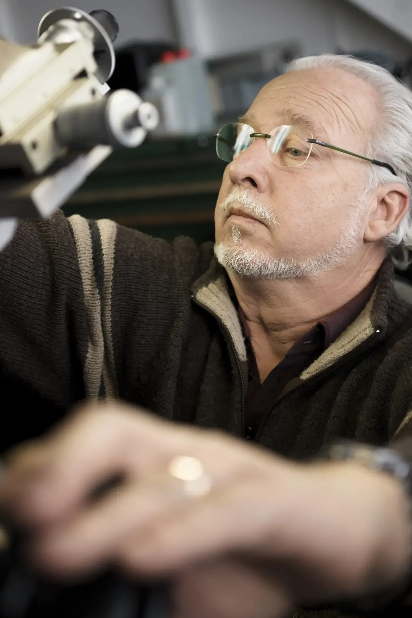 Watchmaker at Greiner Vibrograf examining a precision instrument in the workshop.