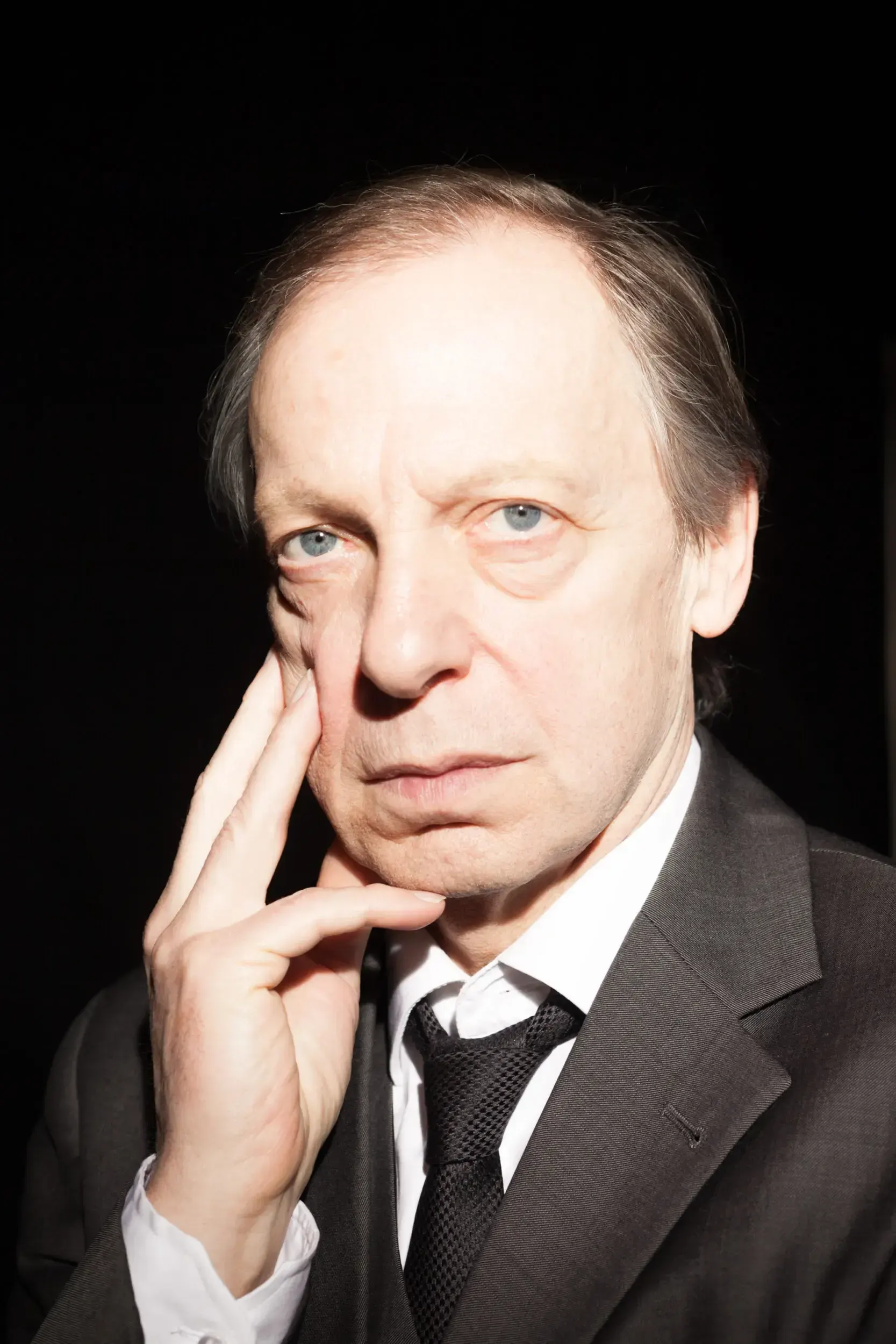 Portrait of actor Hans Kremer in a suit and tie, resting his hand against his cheek.