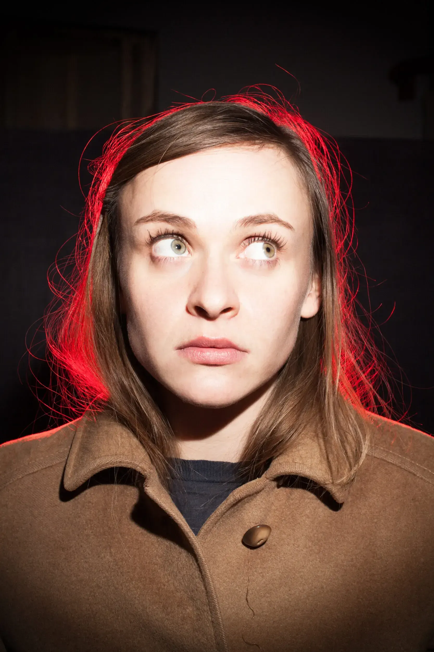 Portrait of actress Henrike Jörissen with red rim lighting, glancing to the side.