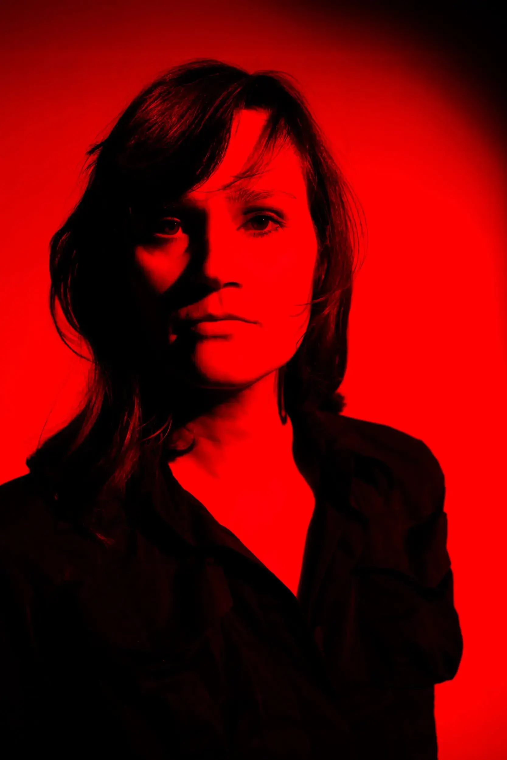 Portrait of Hilke Altefrohne lit entirely in deep red light.
