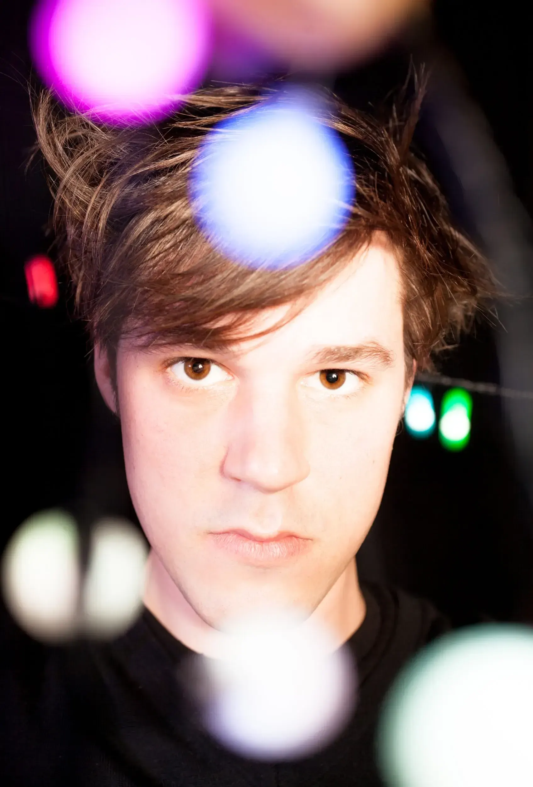 Close-up portrait of Johannes Sima framed by colorful out-of-focus lights.