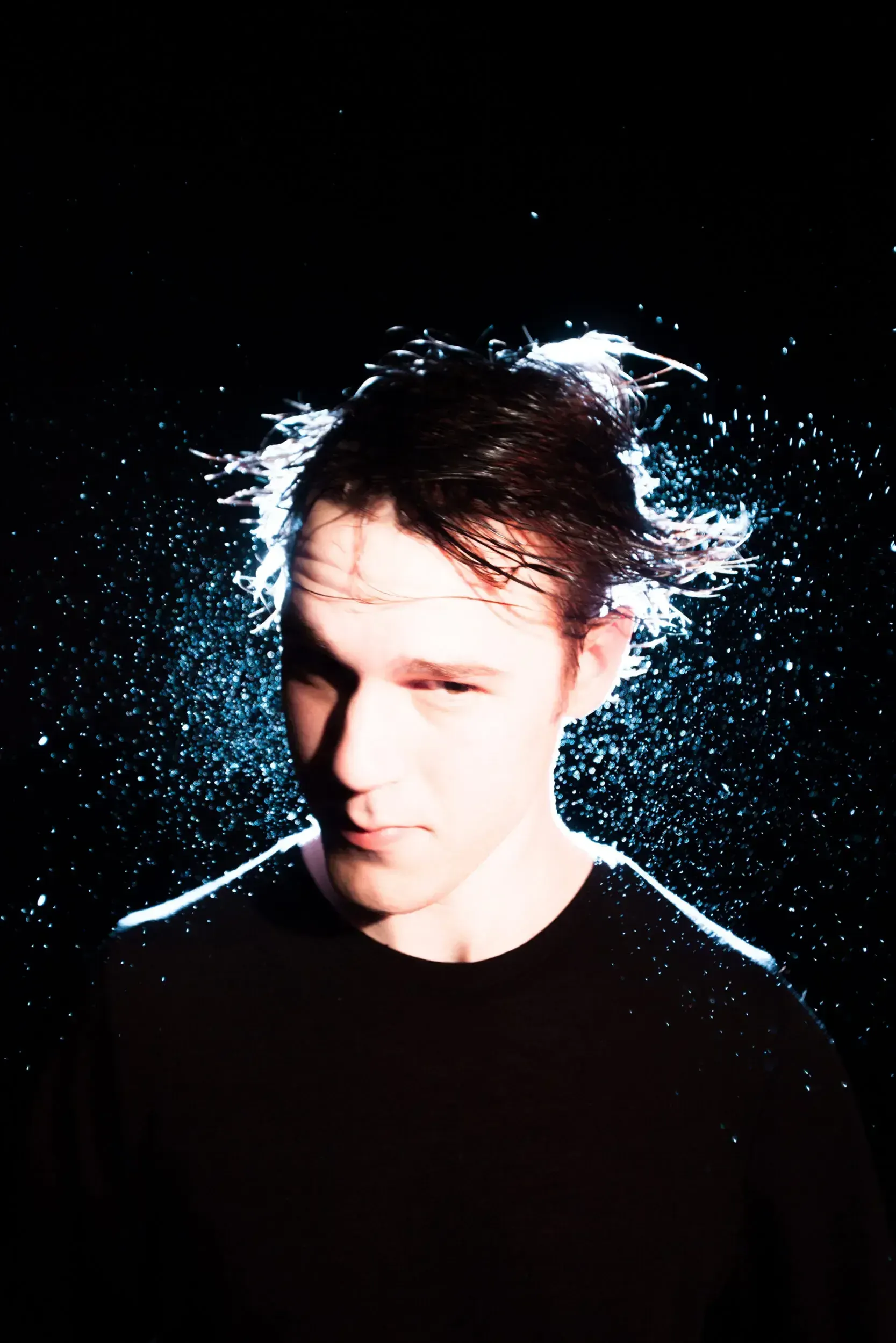 Portrait of Johannes Sima with water splashing dramatically around his head against a black background.