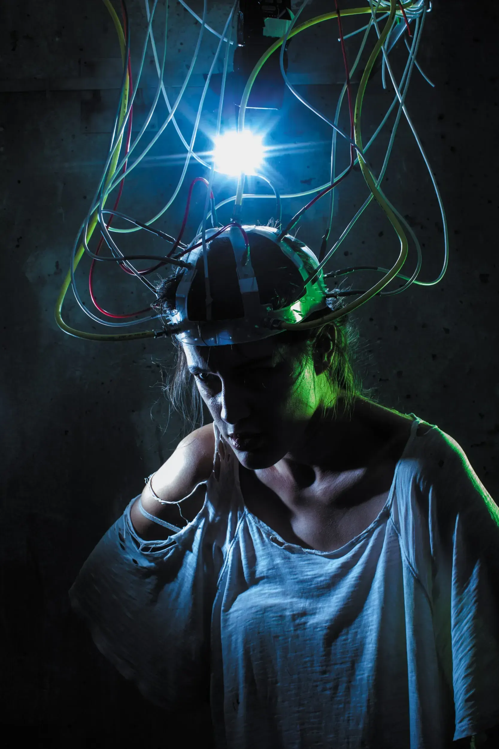 Woman wearing a wire-covered helmet lit in blue, the full-frame source image for the 'Die Jungfrau von Orleans' poster.