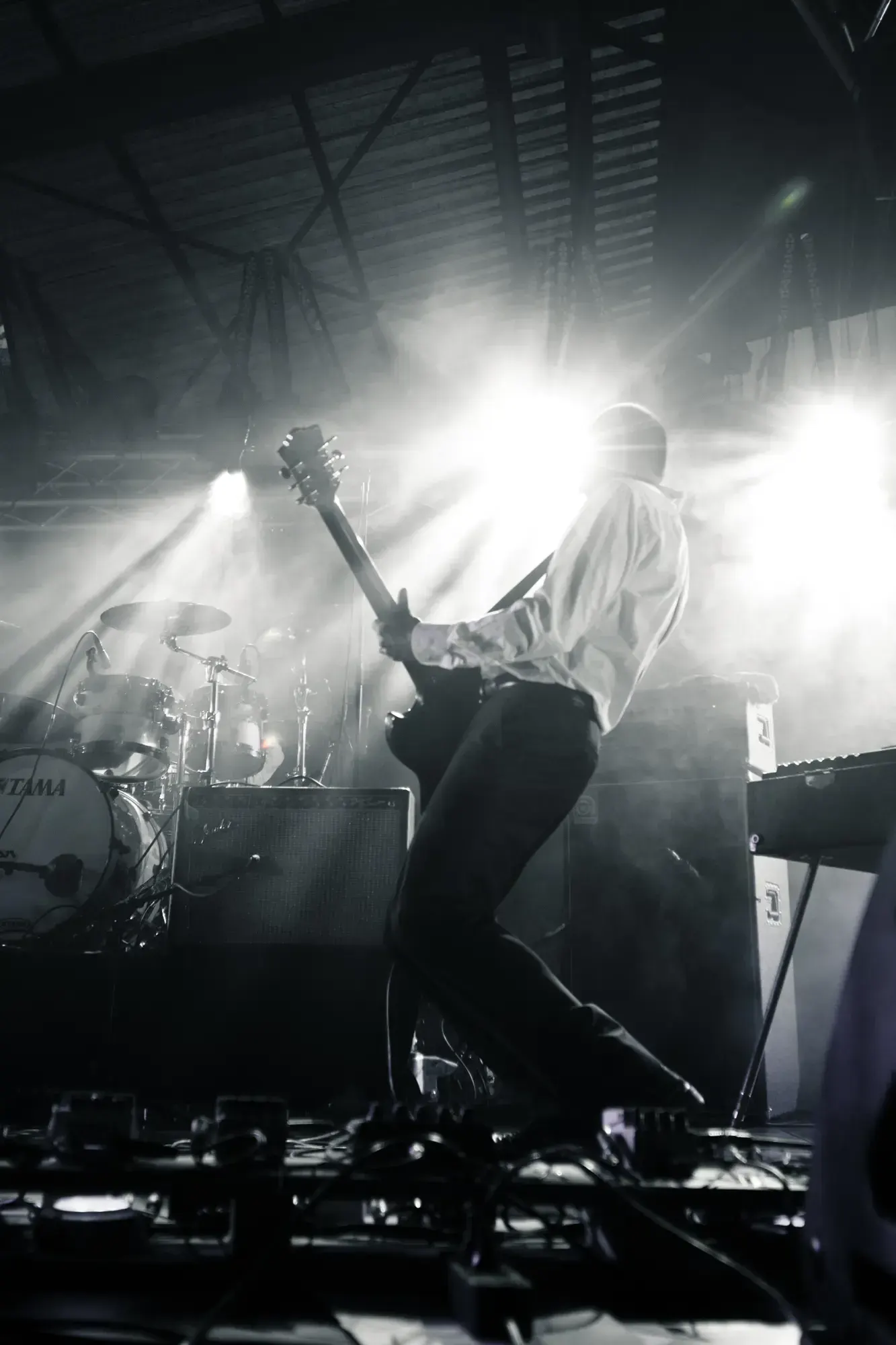Silhouette of a guitarist leaping on stage, backlit by bright stage lights.
