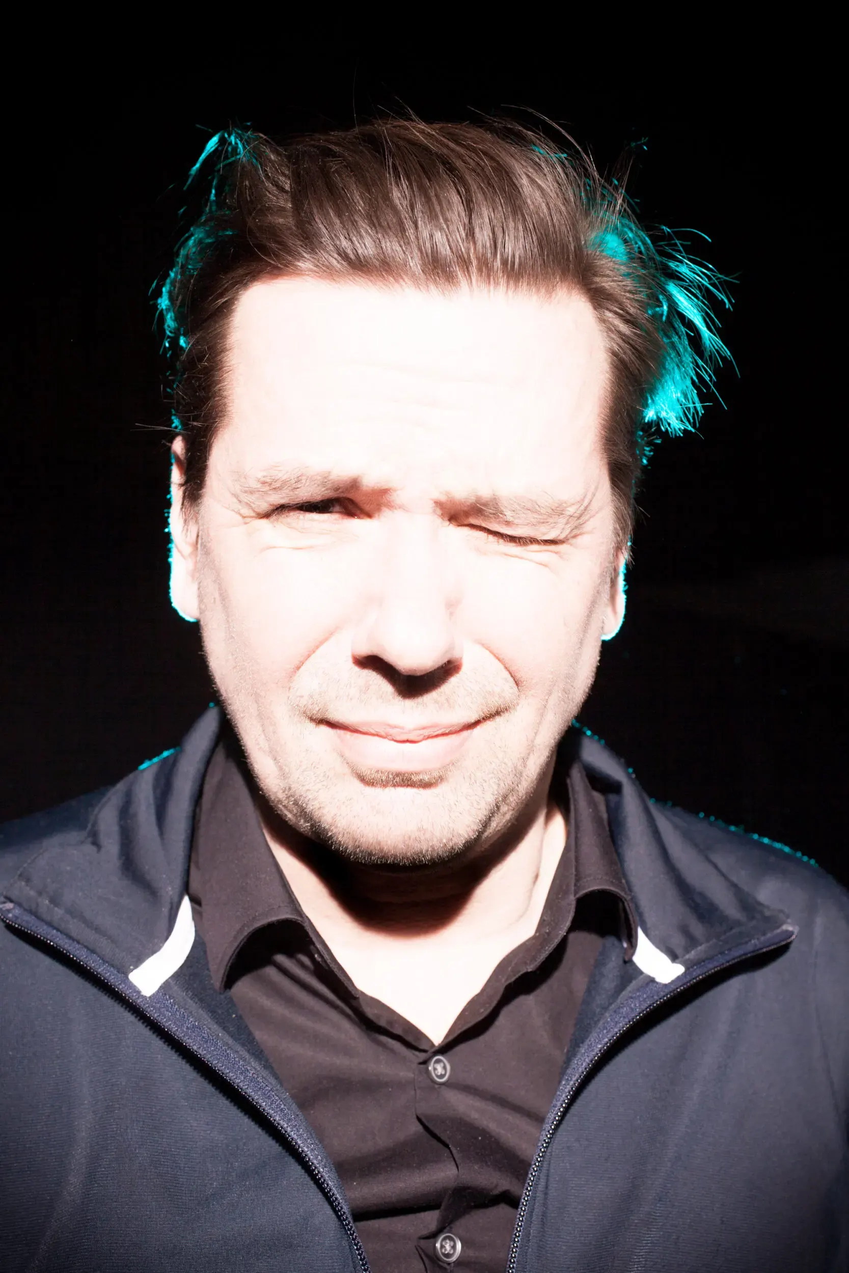 Portrait von Michael Maertens mit geschlossenen Augen vor dunklem Hintergrund